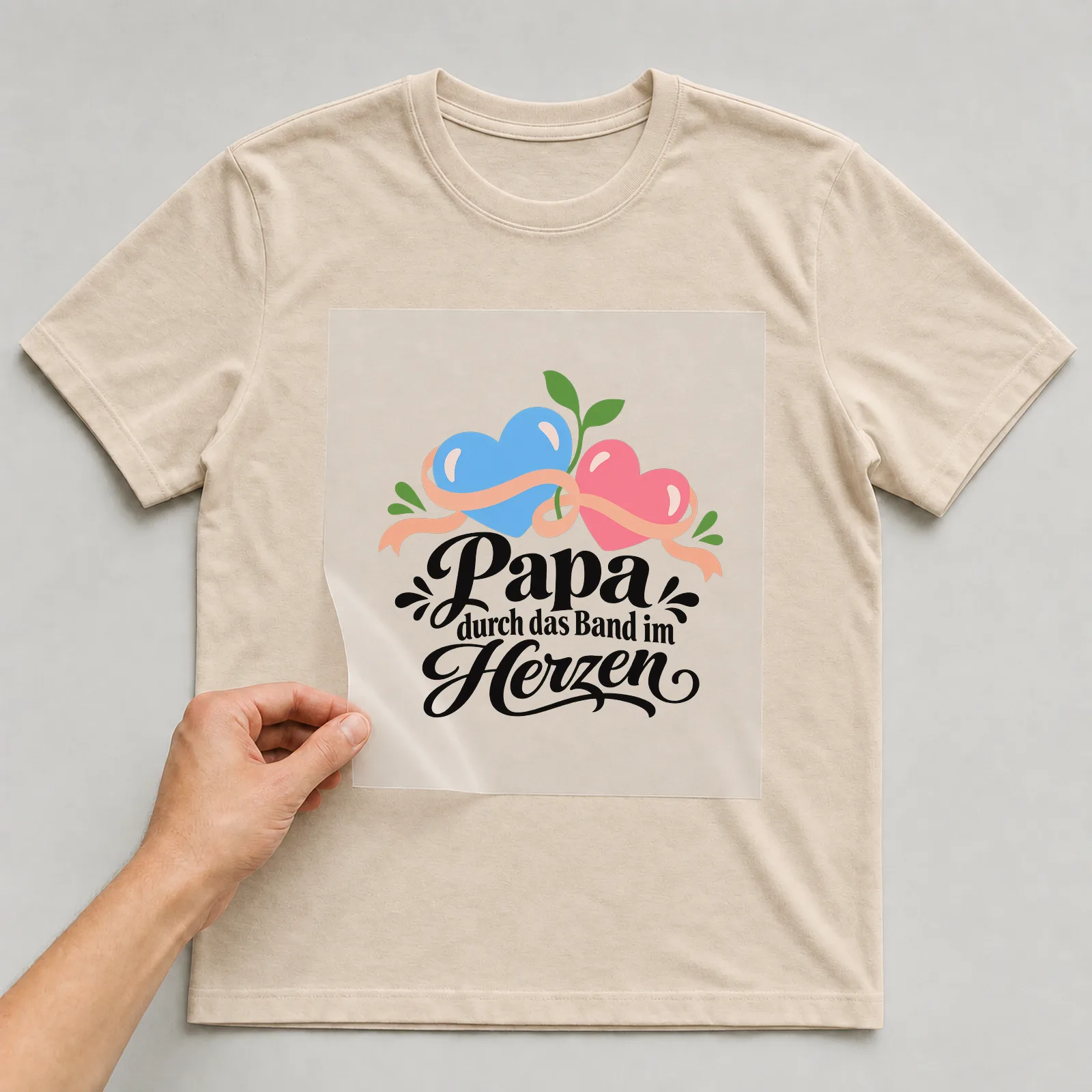 Bügelbild „Papa durch das Band im Herzen“ auf beigem T-Shirt, Folie wird aufgelegt