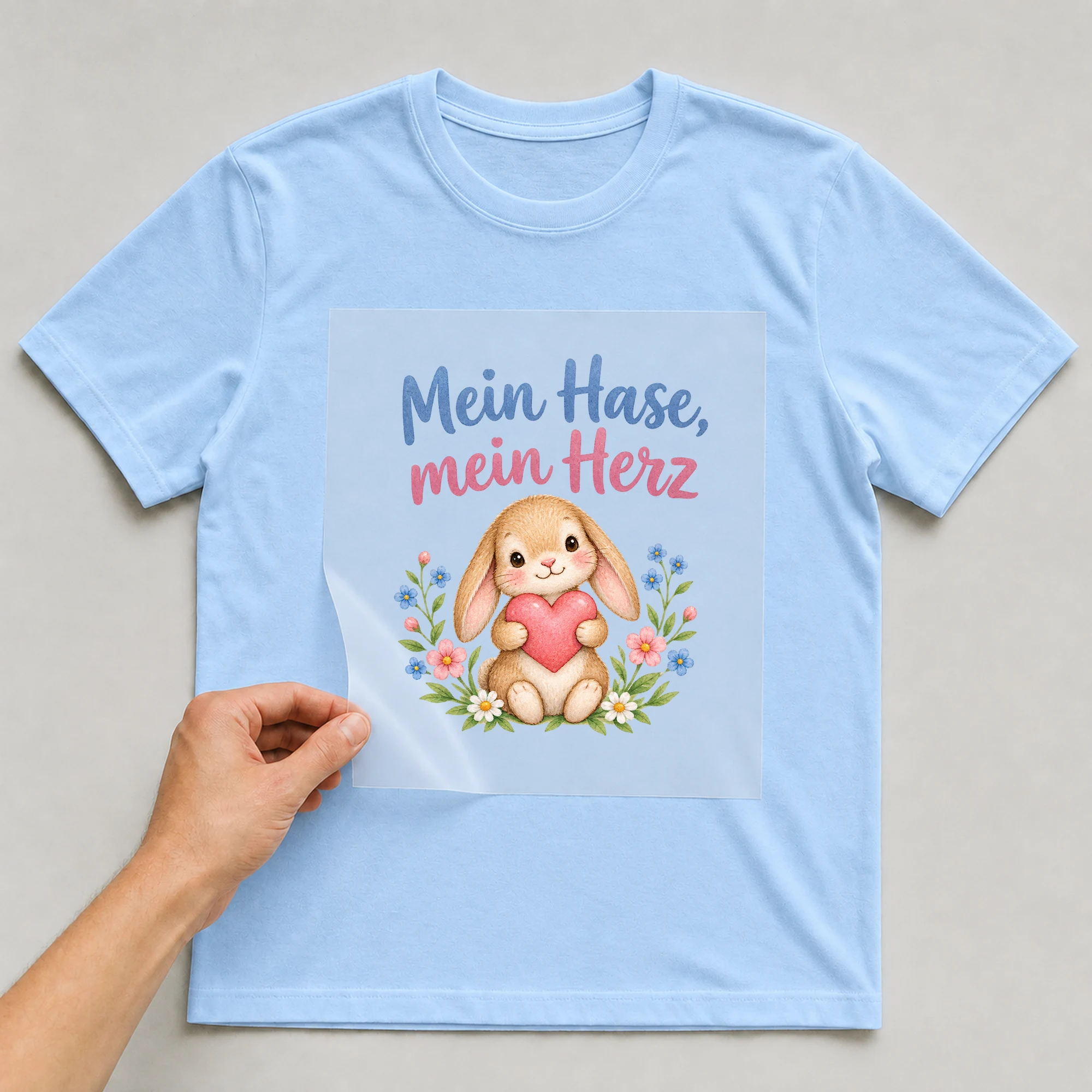 Bügelbild „Mein Hase, mein Herz“ auf babyblauem T-Shirt, Folie wird aufgelegt
