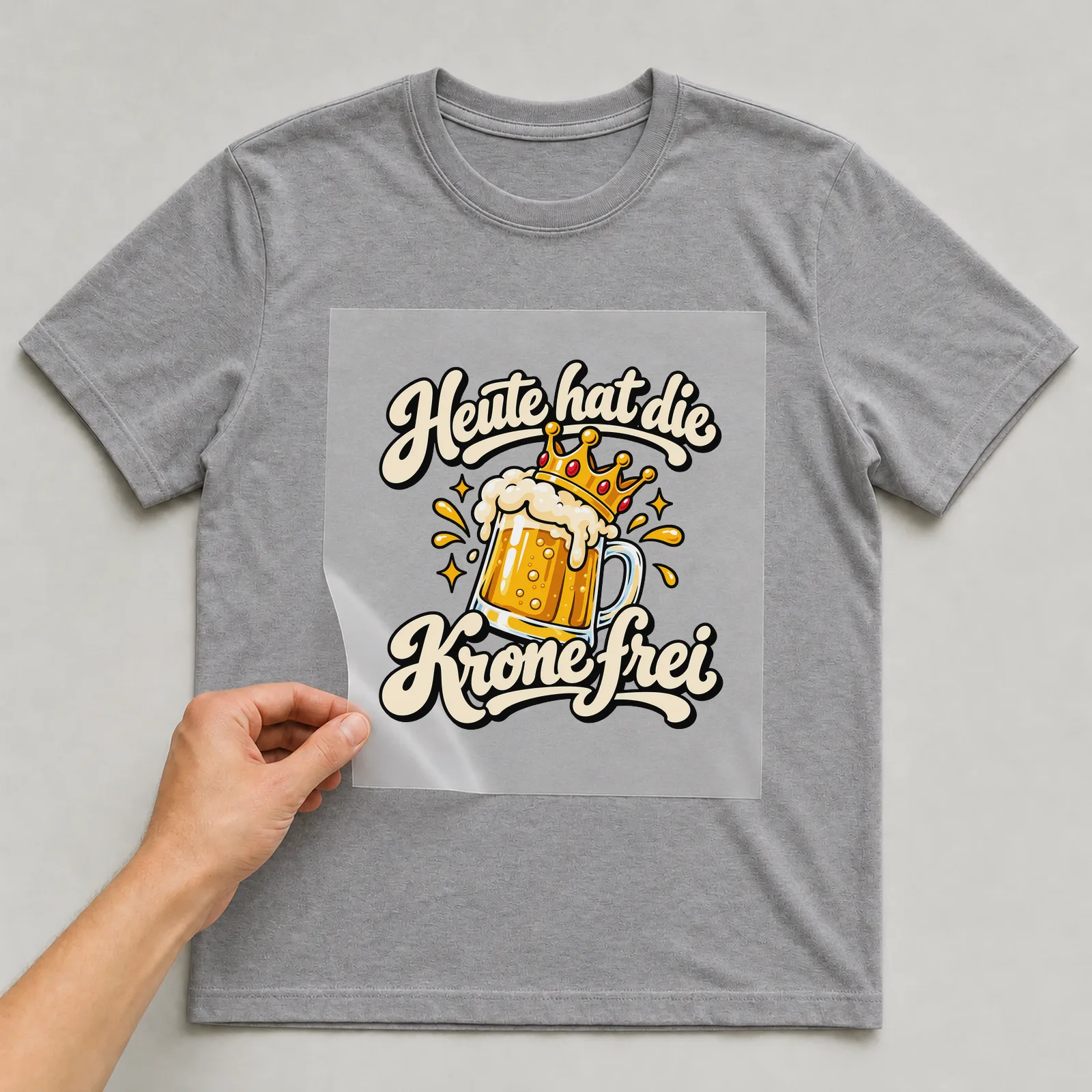 Bügelbild „Heute hat die Krone frei“ auf grauem T-Shirt, Folie wird aufgelegt