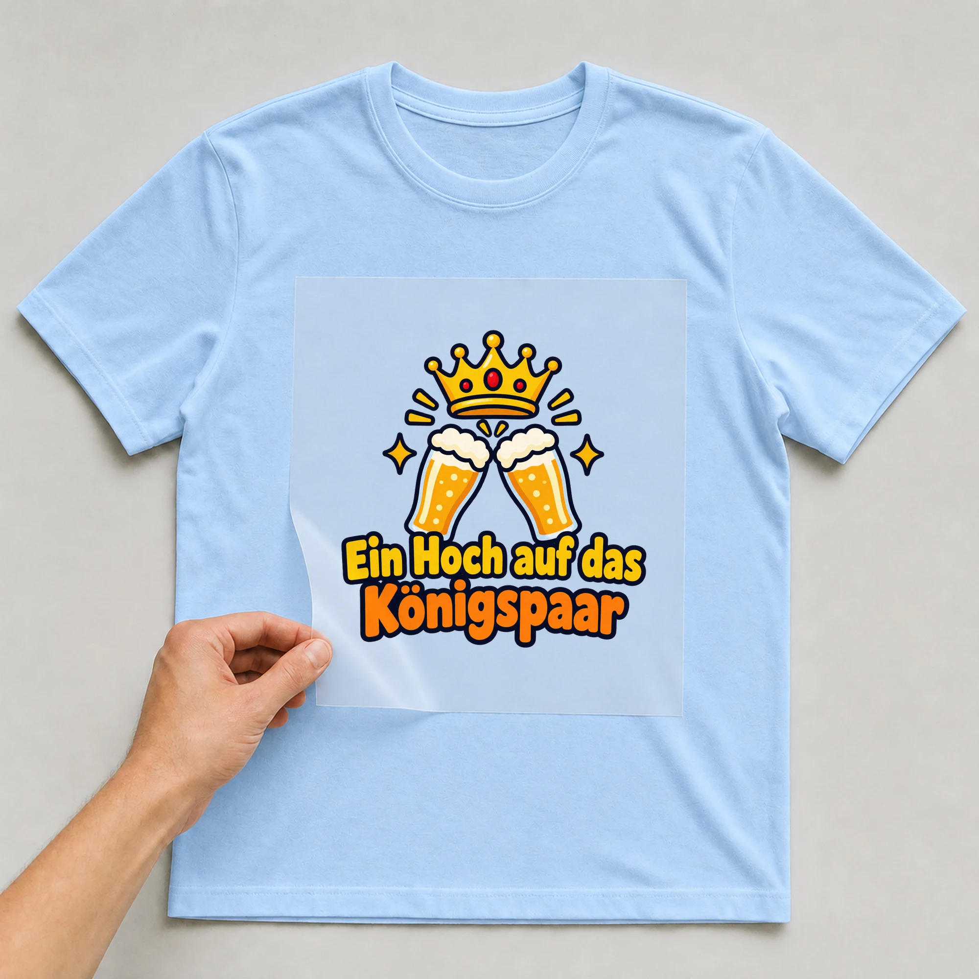 Bügelbild „Ein Hoch auf das Königspaar“ auf babyblauem T-Shirt, Folie wird aufgelegt