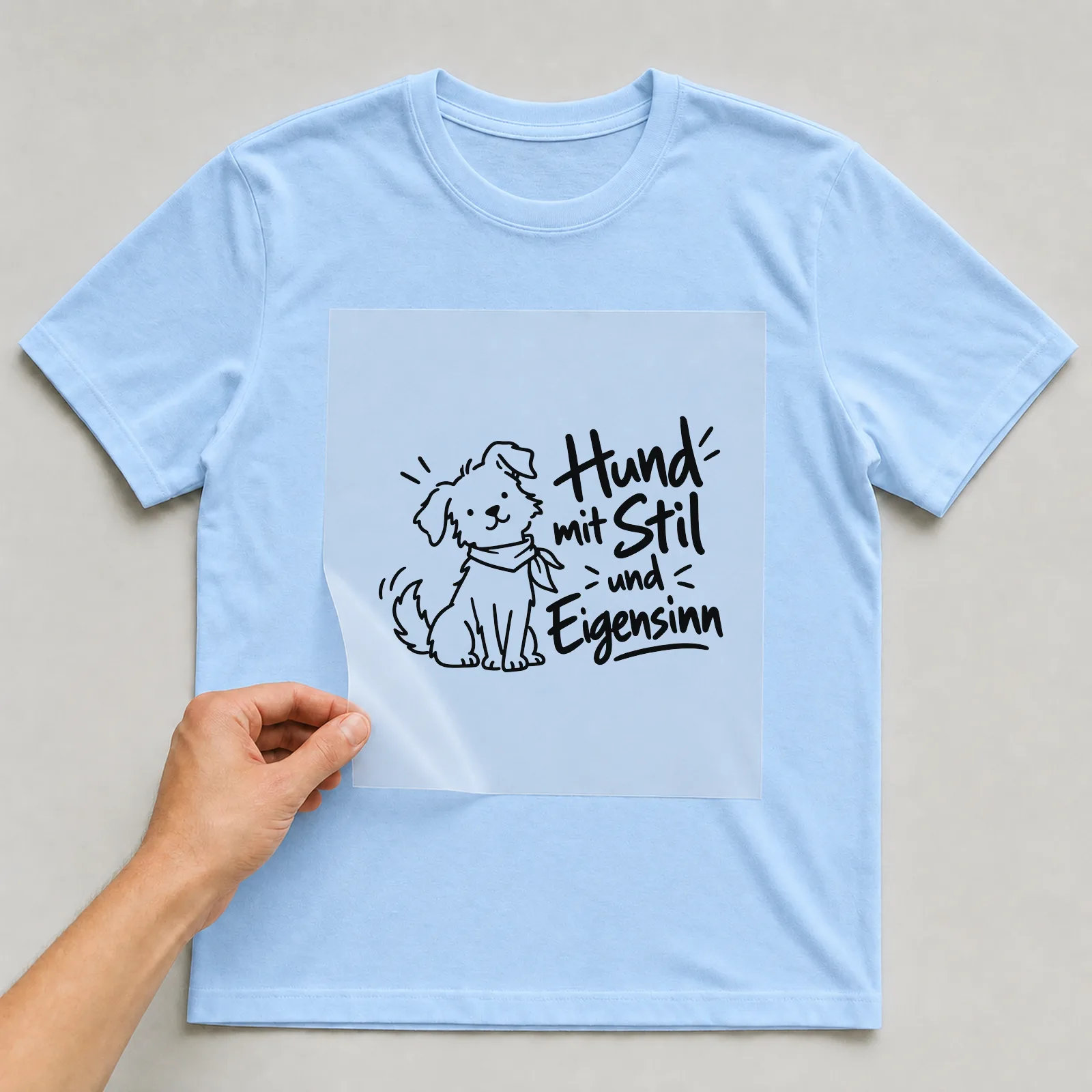 Bügelbild „Hund mit Stil und Eigensinn“ auf hellblauem T-Shirt, Folie wird aufgelegt