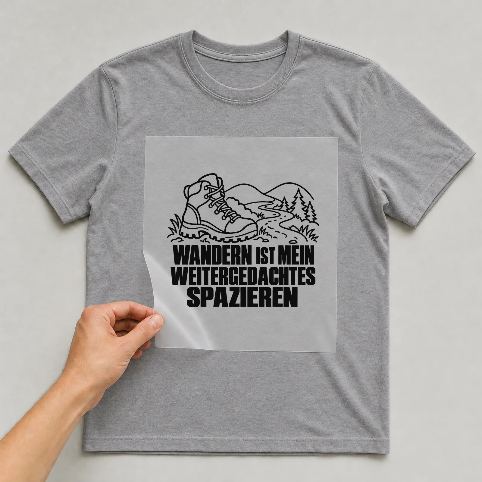 Bügelbild „Wandern ist mein Weitergedachtes spazieren“ auf grauem T-Shirt, Folie wird aufgelegt