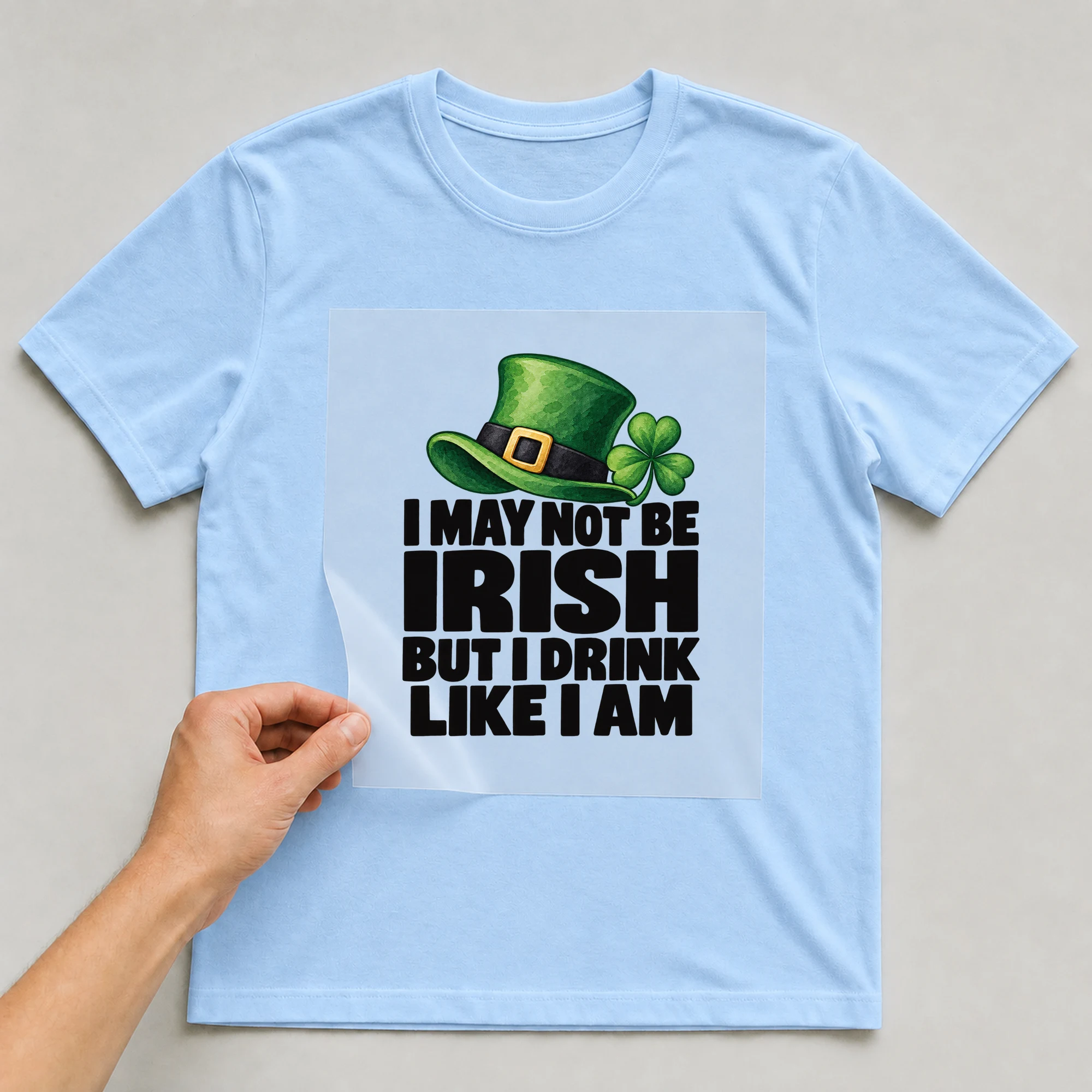 Bügelbild „I May Not Be Irish But I Drink Like I Am“ auf babyblauem T-Shirt, Folie wird aufgelegt