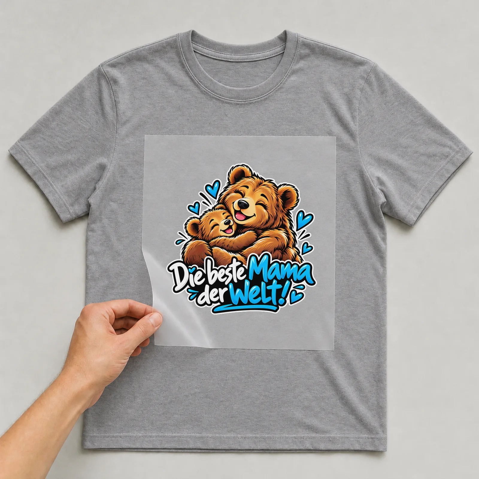 Bügelbild „Die beste Mama der Welt!“ auf grauem T-Shirt, Folie wird aufgelegt