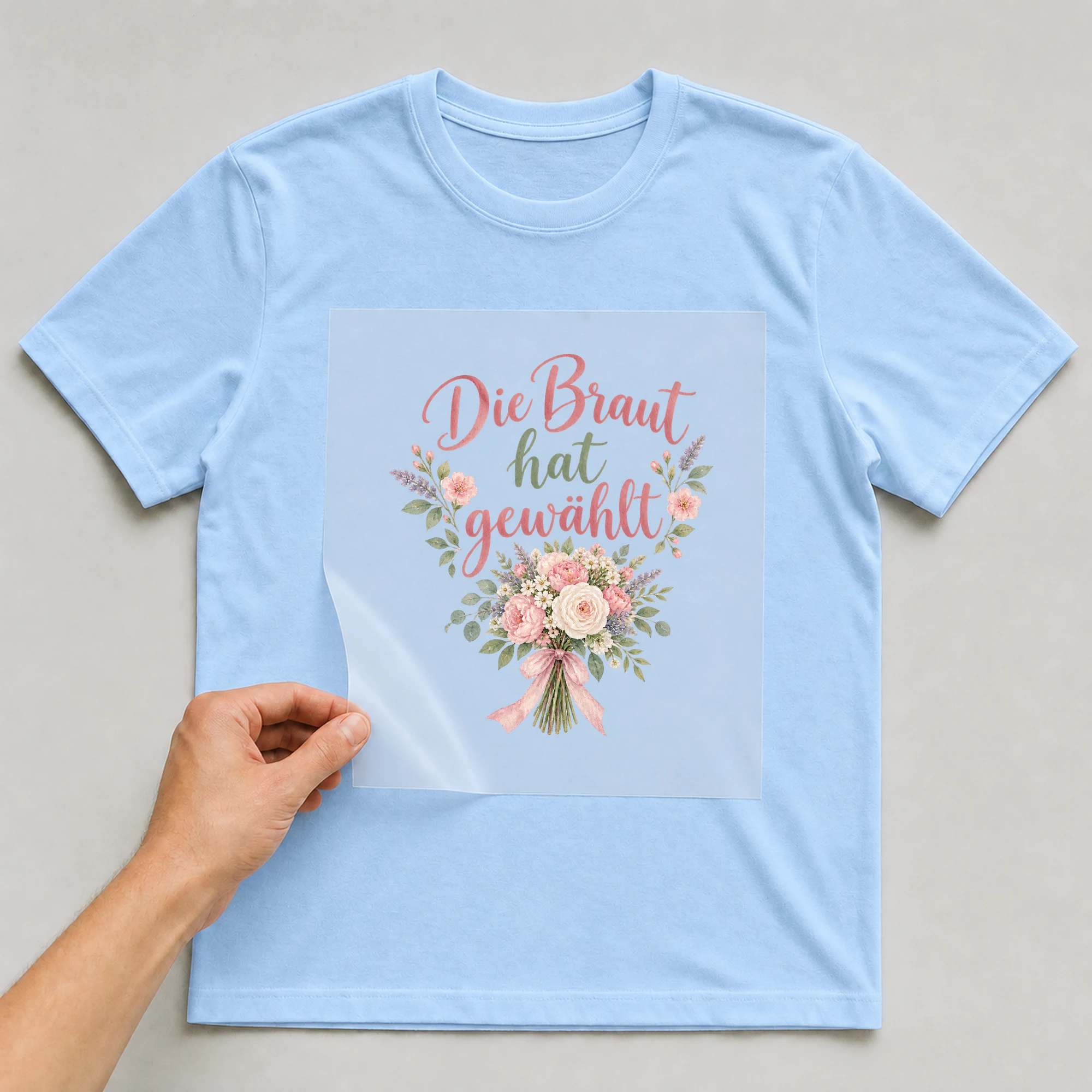 Bügelbild „Die braut hat gewaehlt“ auf babyblauem T-Shirt, Folie wird aufgelegt