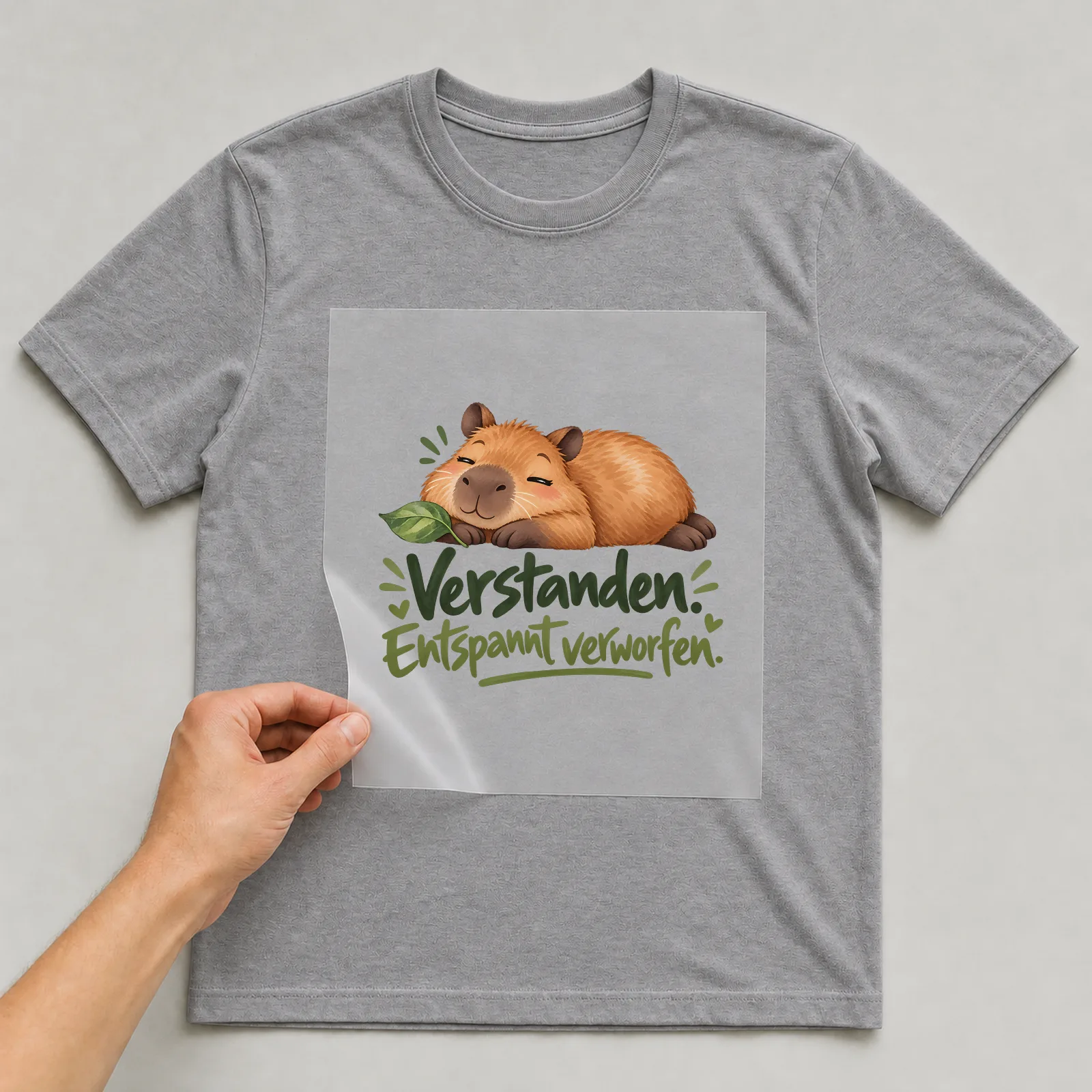 Bügelbild „Verstanden. Entspannt verworfen.“ auf grauem T-Shirt, Folie wird aufgelegt