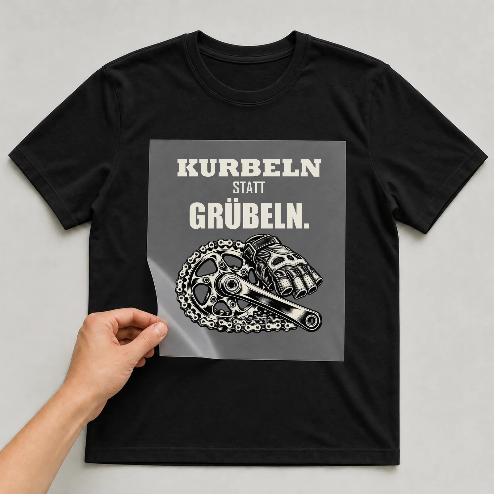 Bügelbild „Kurbeln statt grübeln“ auf schwarzem T-Shirt, Folie wird aufgelegt