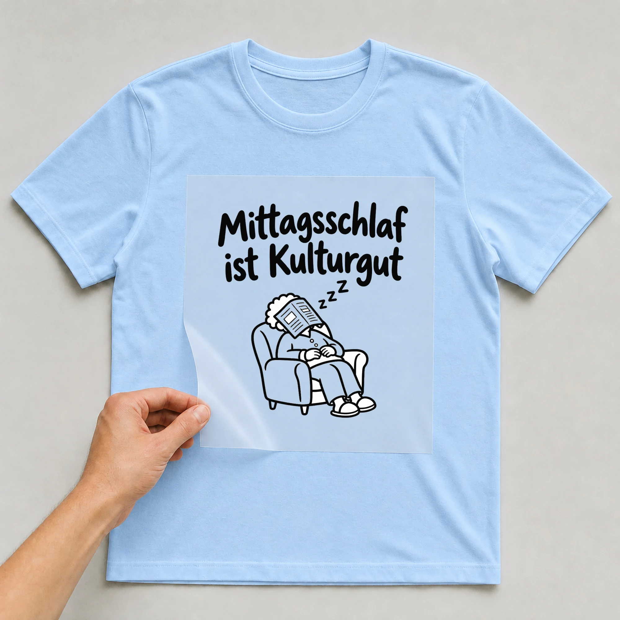 Bügelbild „Mittagsschlaf ist Kulturgut“ auf babyblauem T-Shirt, Folie wird aufgelegt