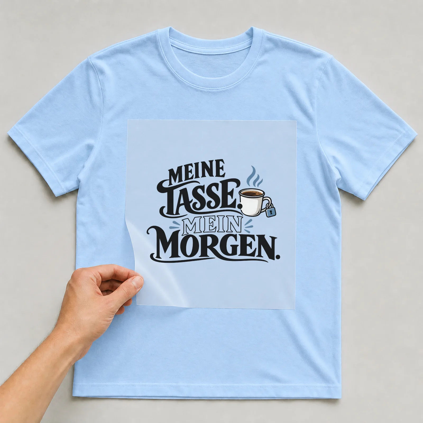 Bügelbild „Meine Tasse. Mein morgen.“ auf hellblauem T-Shirt, Folie wird aufgelegt