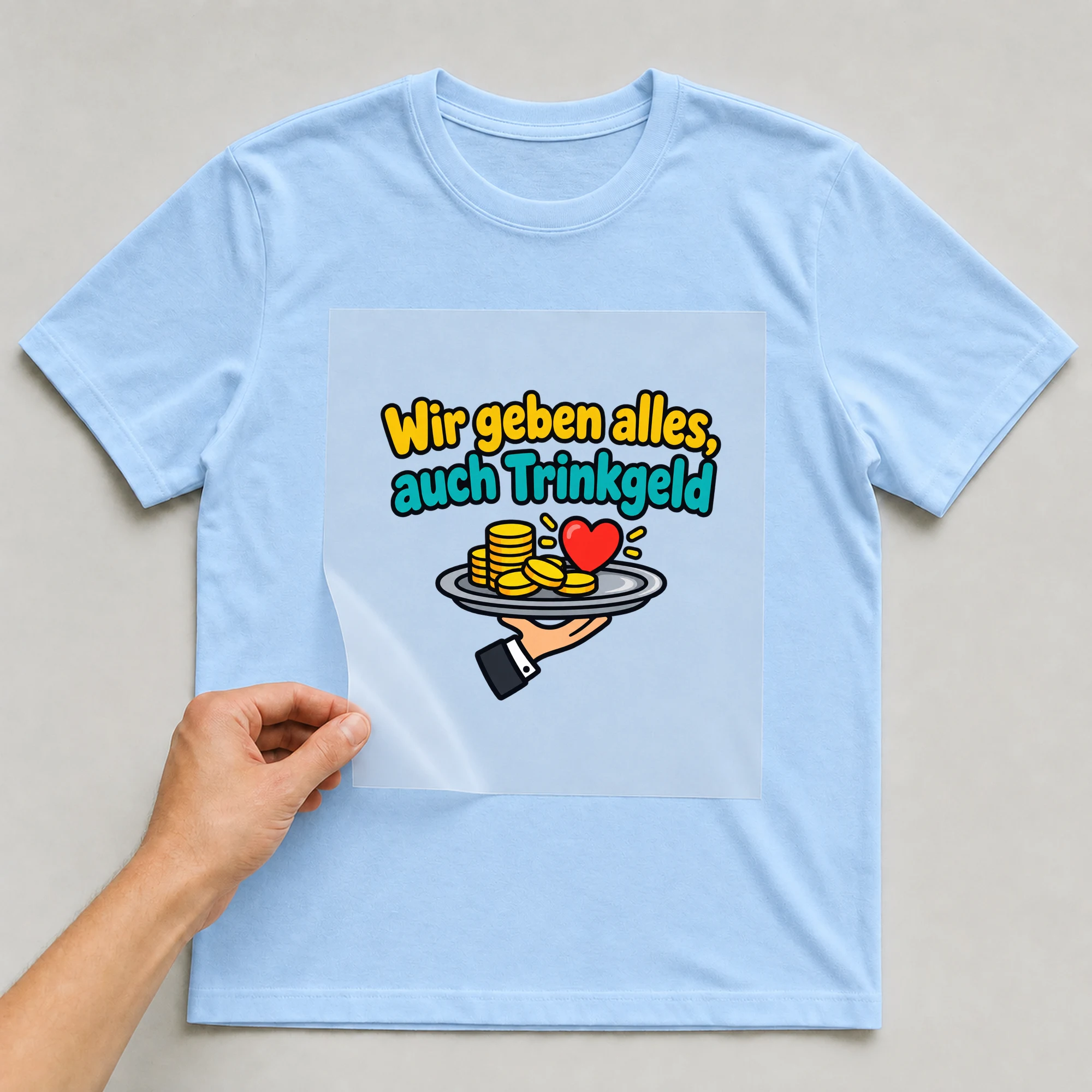 Bügelbild „Wir geben alles, auch Trinkgeld“ auf babyblauem T-Shirt, Folie wird aufgelegt