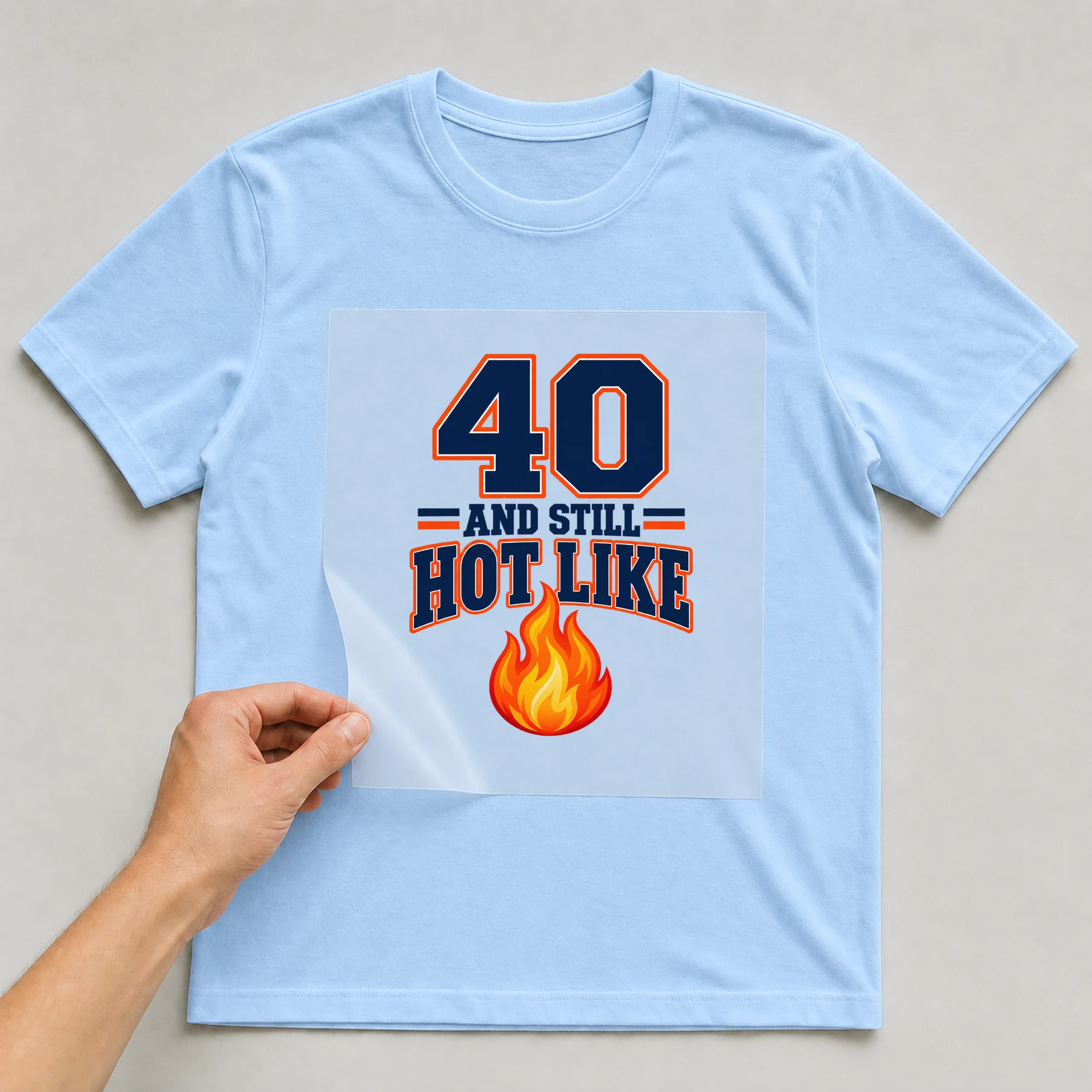 Bügelbild „40 And Still Hot Like“ auf babyblauem T-Shirt, Folie wird aufgelegt