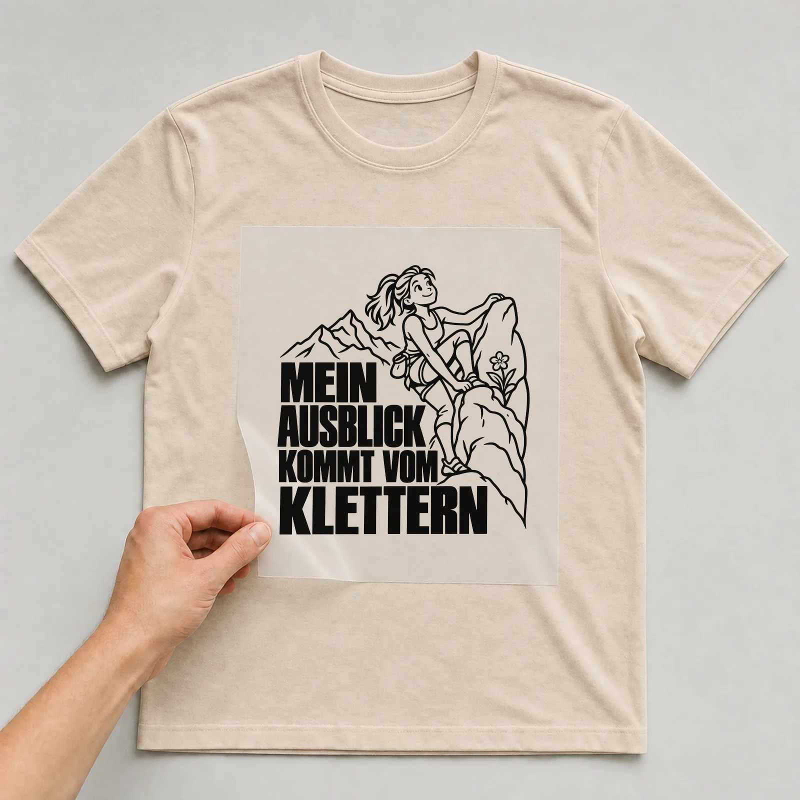 Bügelbild „Mein Ausblick kommt vom Klettern“ auf beigem T-Shirt, Folie wird aufgelegt