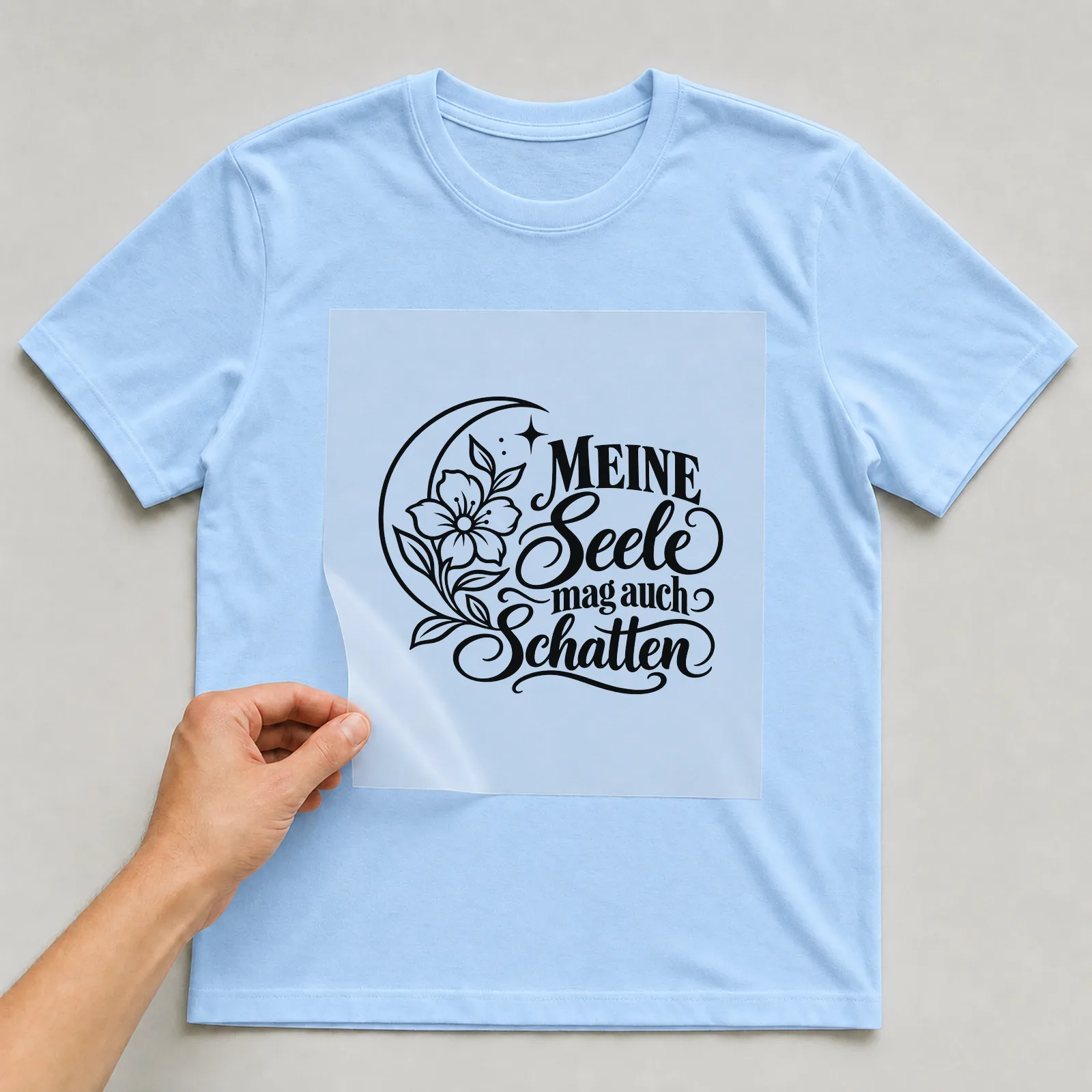 Bügelbild „MEINE Seele mag auch Schatten“ auf hellblauem T-Shirt, Folie wird aufgelegt