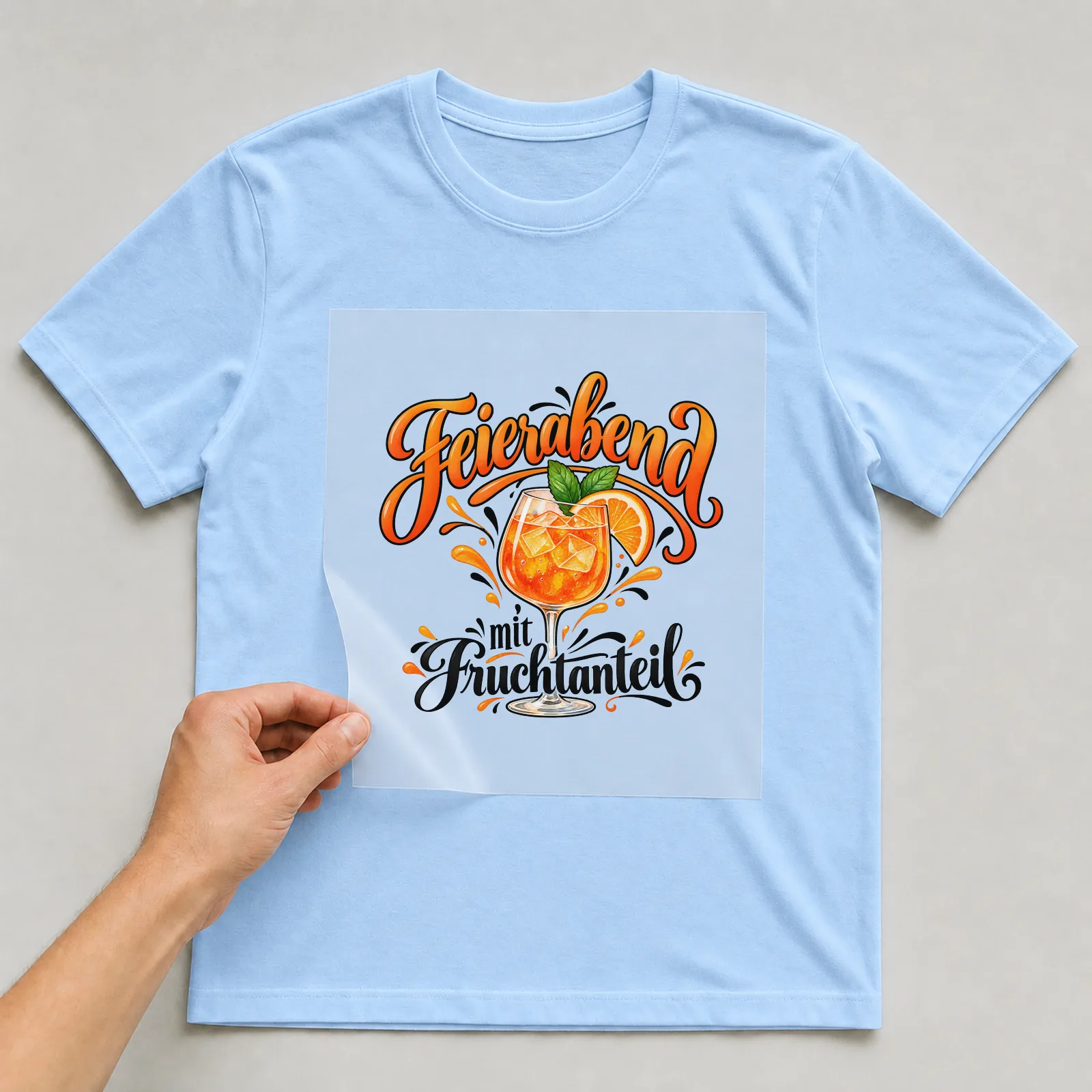 Bügelbild „Feierabend mit Fruchtanteil“ auf hellblauem T-Shirt, Folie wird aufgelegt