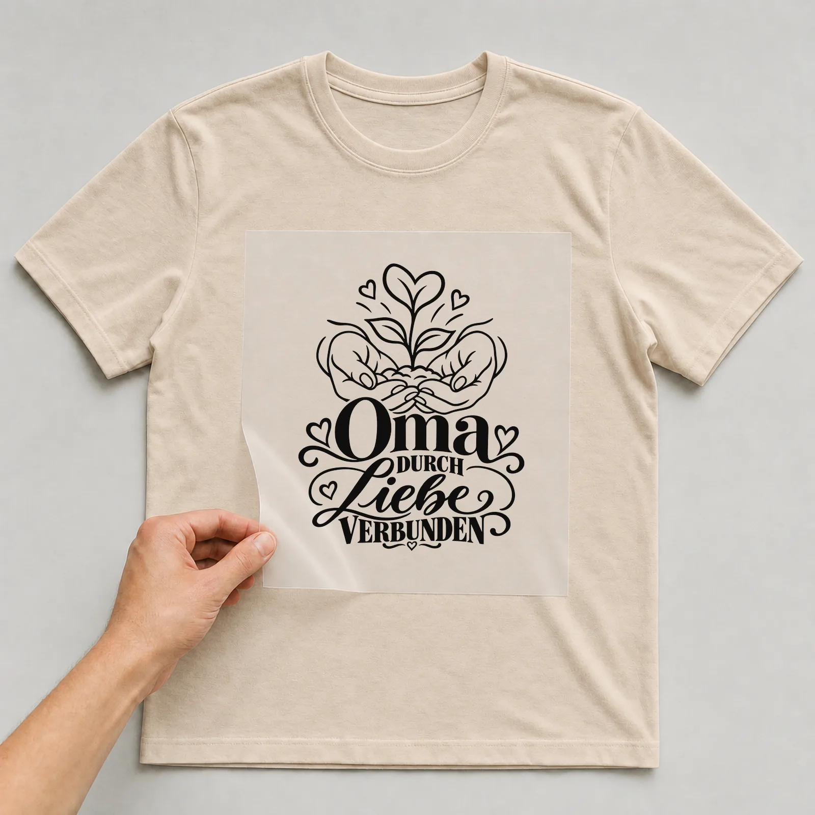 Bügelbild „Oma DURCH Liebe VERBUNDEN“ auf beigem T-Shirt, Folie wird aufgelegt