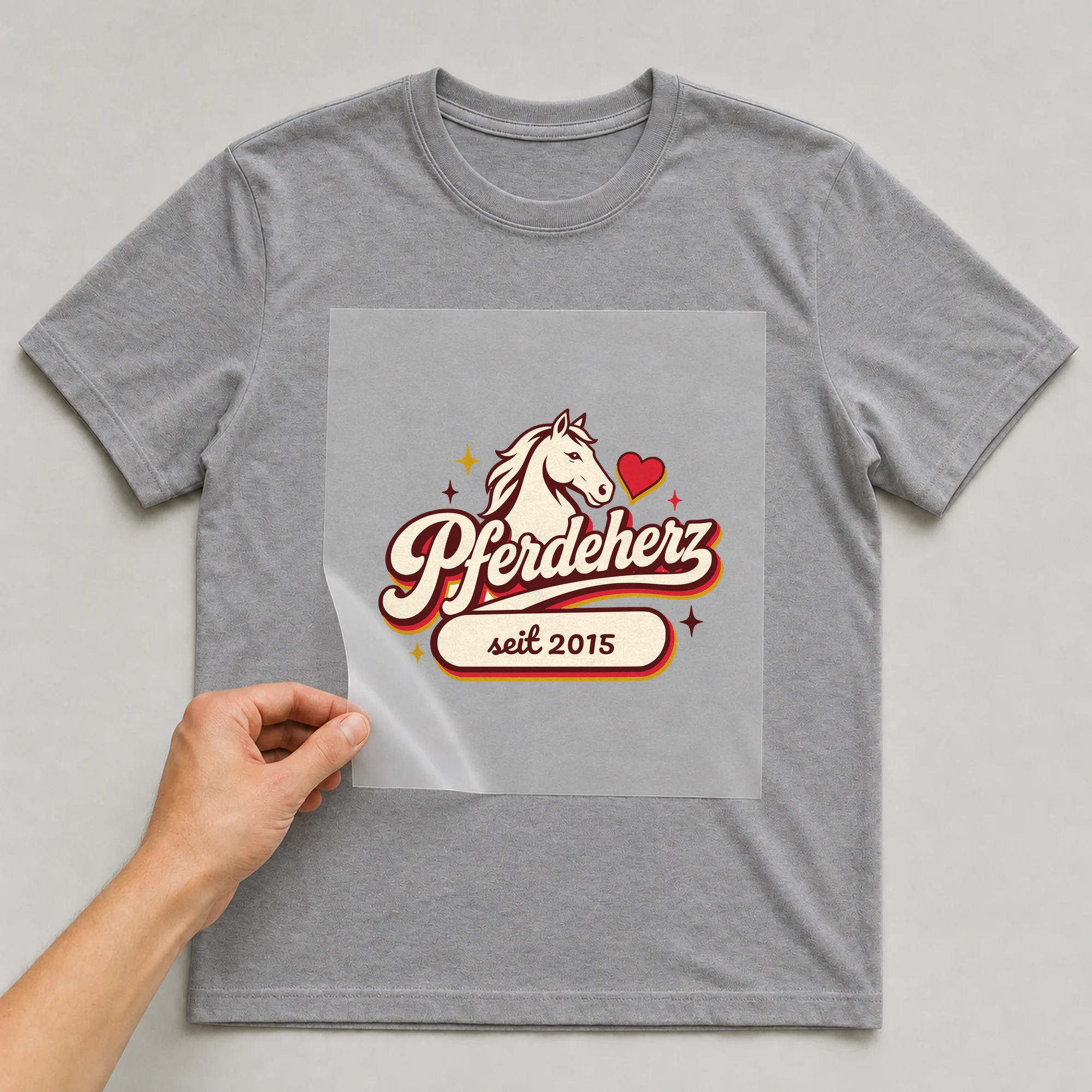 Bügelbild Pferdeherz mit Jahr auf grauem T-Shirt, Folie wird aufgelegt