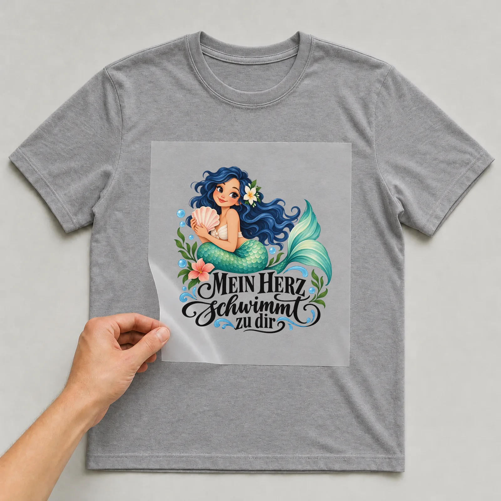Bügelbild „MEIN HERZ schwimmt zu dir“ auf grauem T-Shirt, Folie wird aufgelegt