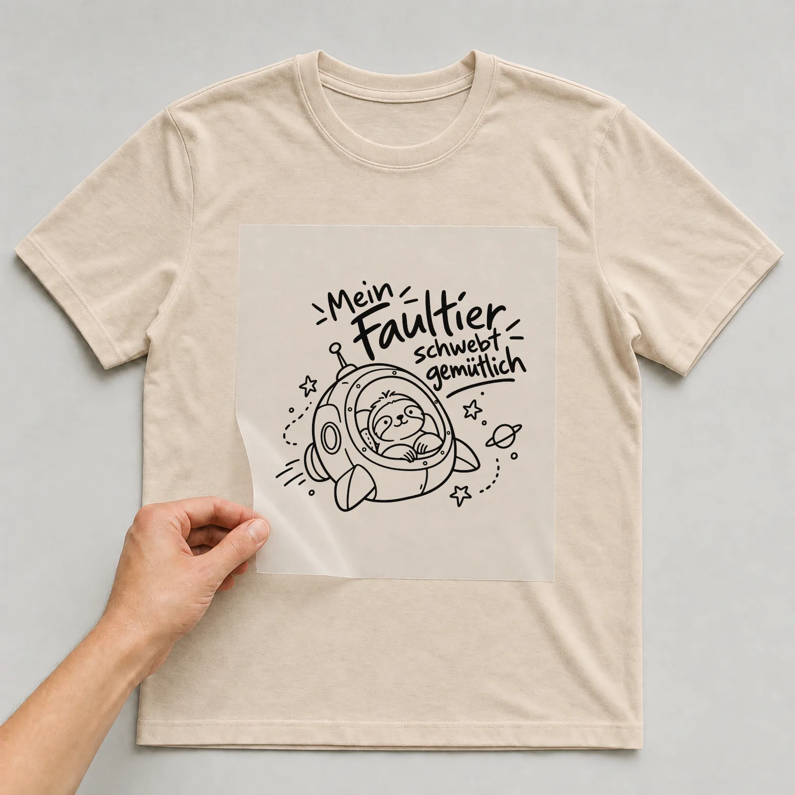 Bügelbild „Mein Faultier schwebt gemütlich“ auf beigem T-Shirt, Folie wird aufgelegt
