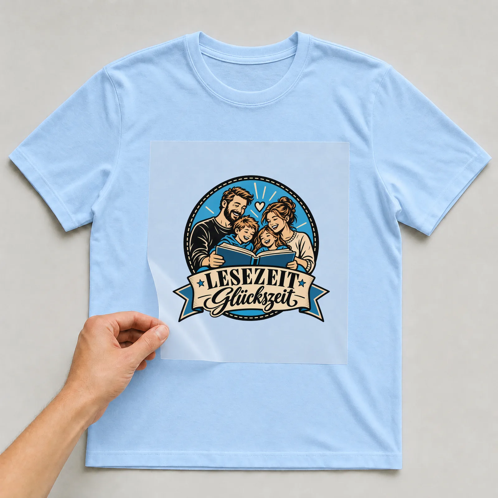 Bügelbild „Lesezeit Glückszeit“ auf hellblauem T-Shirt, Folie wird aufgelegt