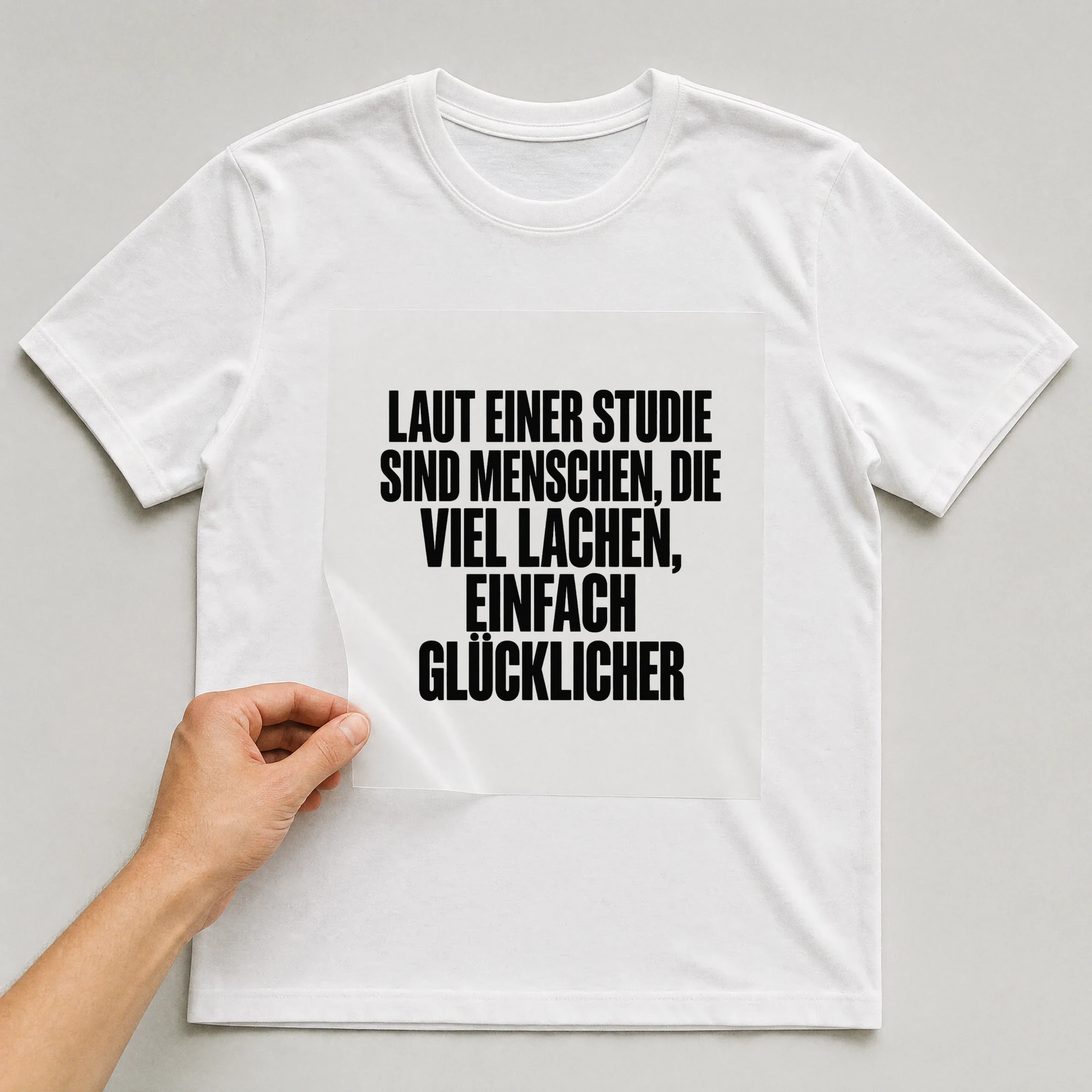 Bügelbild „Laut einer Studie sind Menschen, die viel lachen, einfach glücklicher“ auf weißem T-Shirt, Folie wird aufgelegt