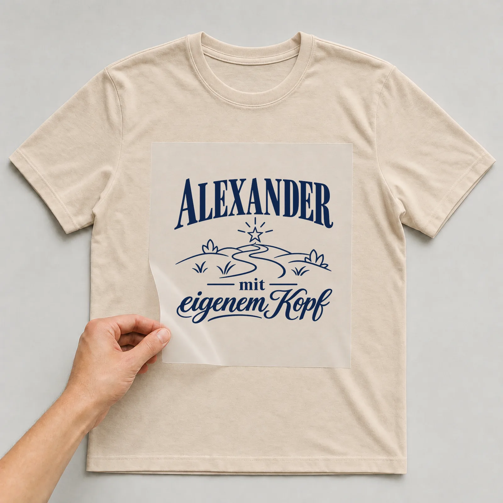 Bügelbild „Alexander mit eigenem Kopf“ auf beigem T-Shirt, Folie wird aufgelegt