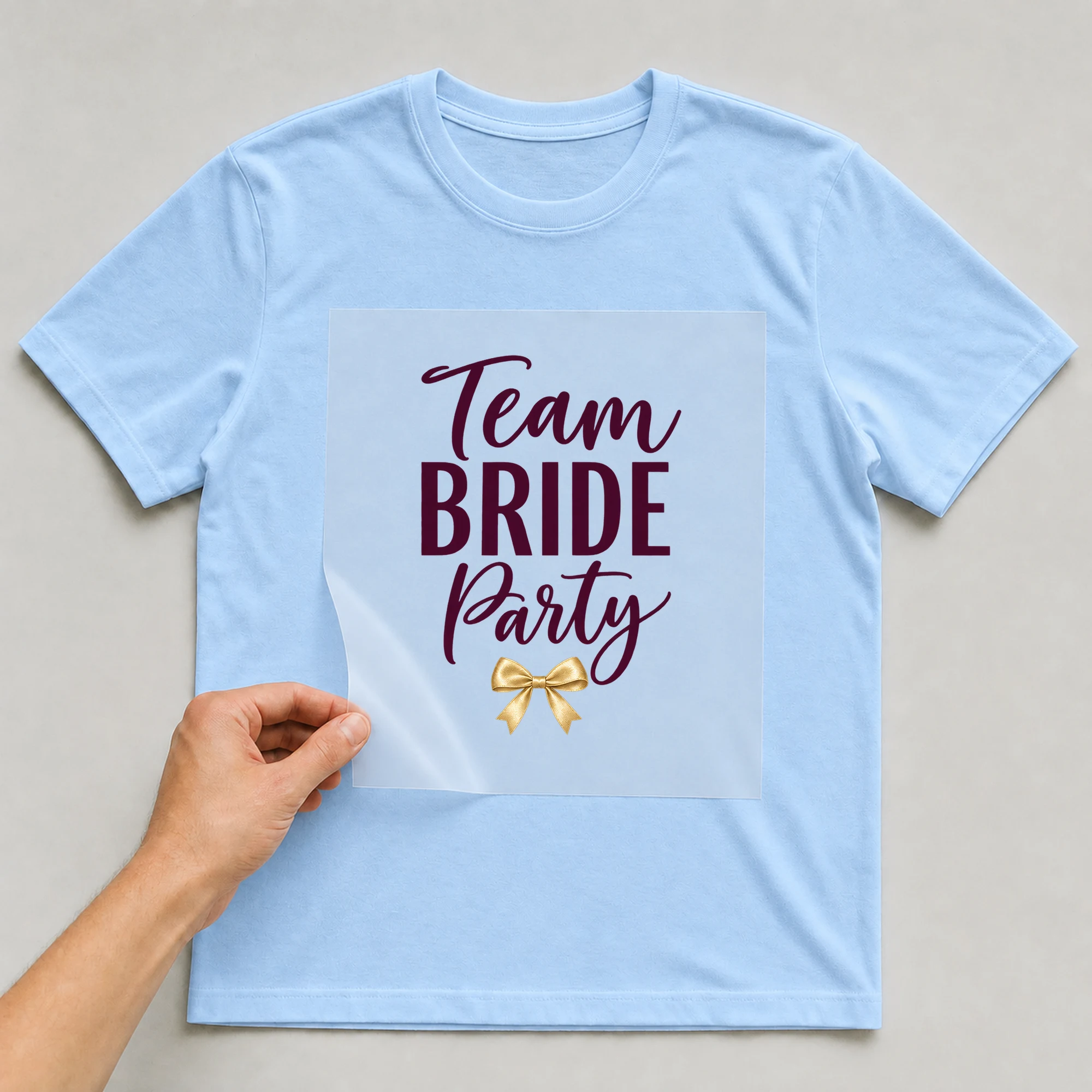 Bügelbild „Team BRIDE Party“ auf babyblauem T-Shirt, Folie wird aufgelegt