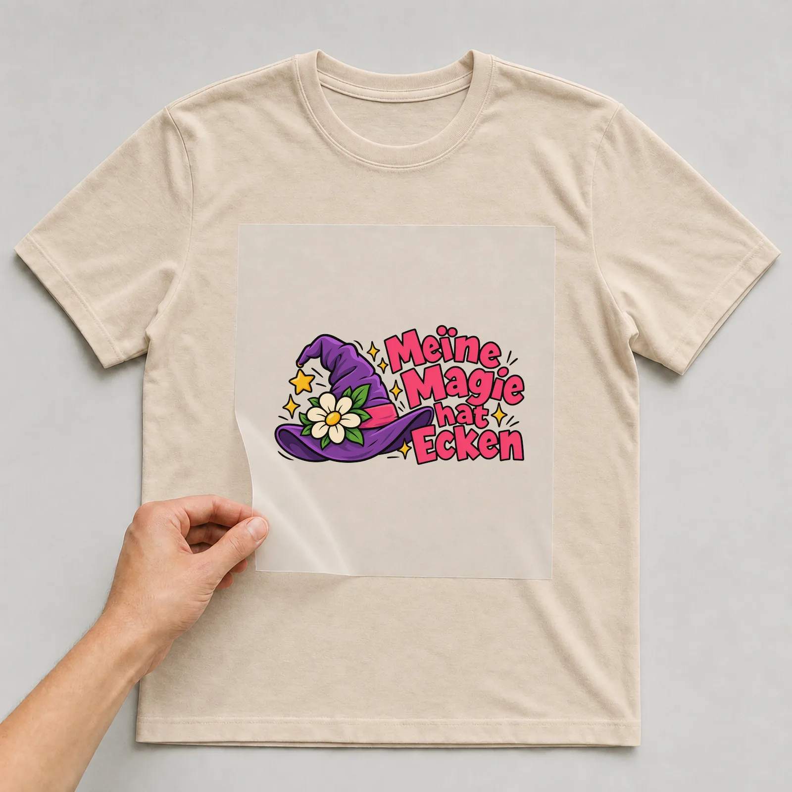 Bügelbild „Meine Magie hat Ecken“ auf beigem T-Shirt, Folie wird aufgelegt