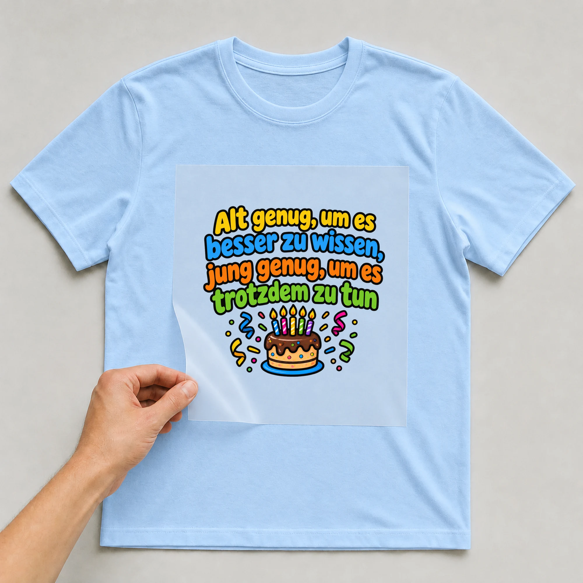 Bügelbild „Alt genug um es besser zu“ auf babyblauem T-Shirt, Folie wird aufgelegt