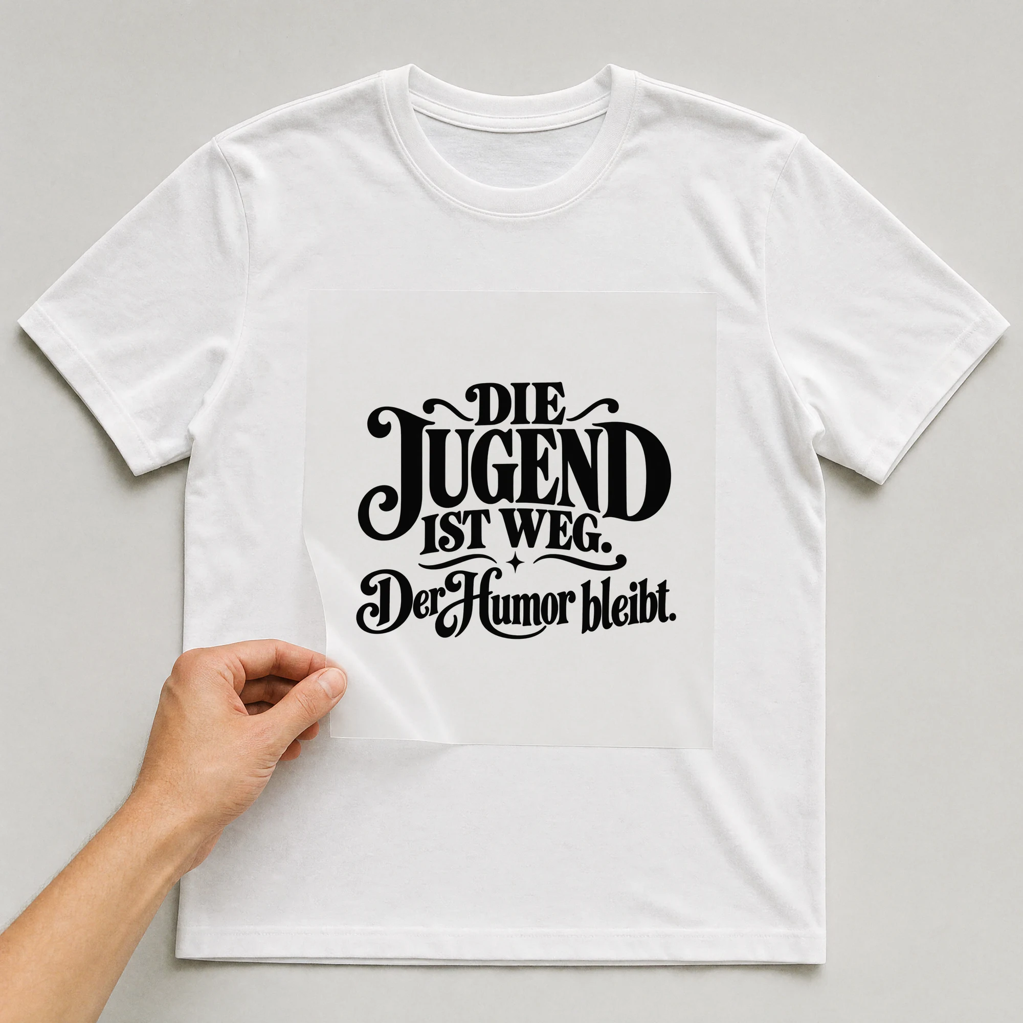 Bügelbild „Die Jugend ist weg. Der Humor bleibt.“ auf weißem T-Shirt, Folie wird aufgelegt