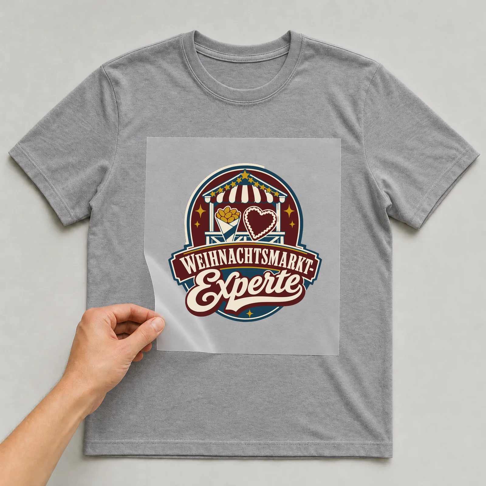 Bügelbild Weihnachtsmarkt-Experte auf grauem T-Shirt, Folie wird aufgelegt