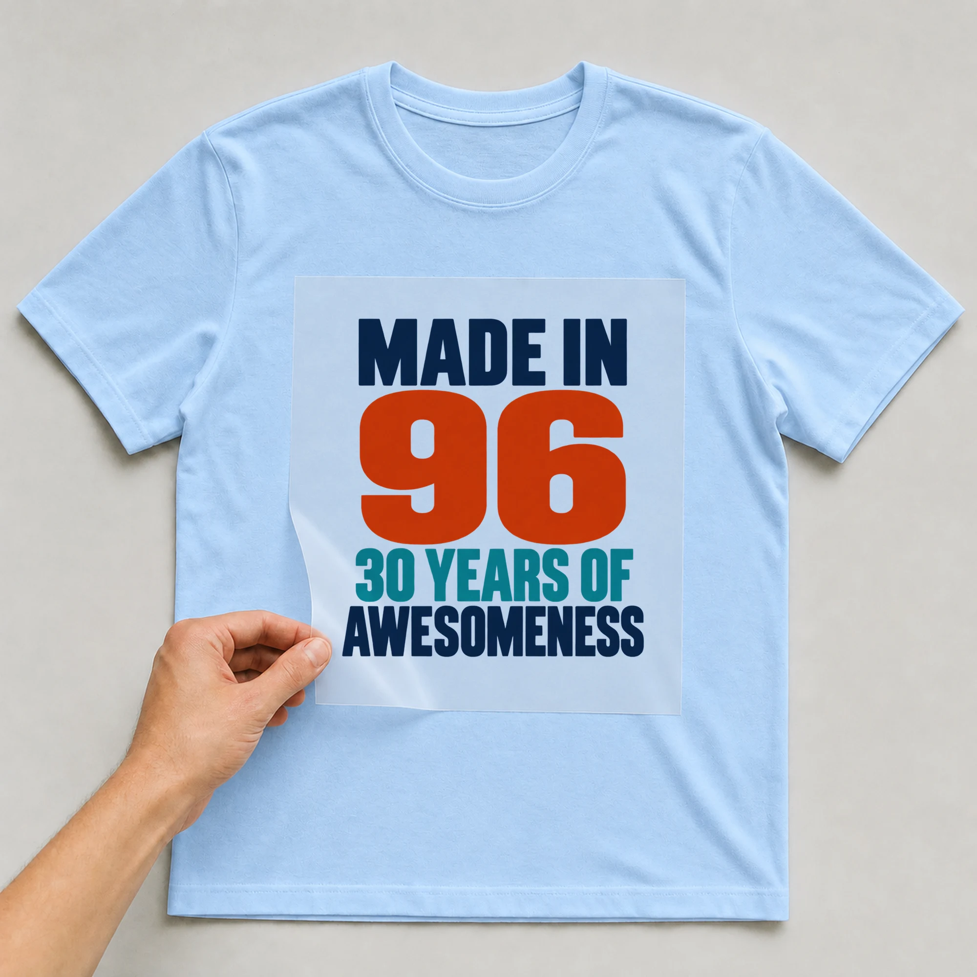 Bügelbild „Made In 96 30 Years Of Awesomeness“ auf babyblauem T-Shirt, Folie wird aufgelegt