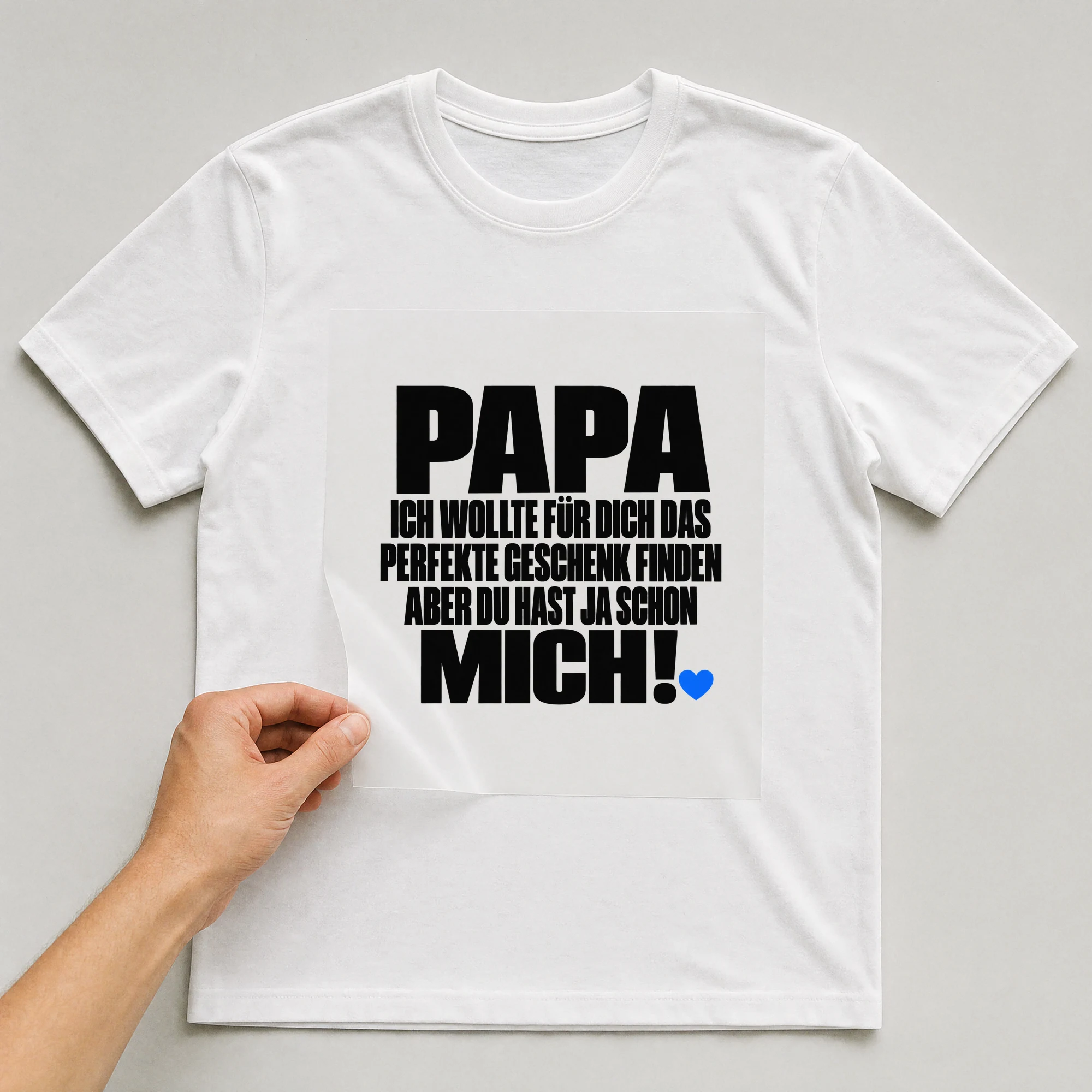 Bügelbild „Papa ich wollte für dich das perfekte Geschenk finden aber du hast ja schon“ auf weißem T-Shirt, Folie wird aufgelegt