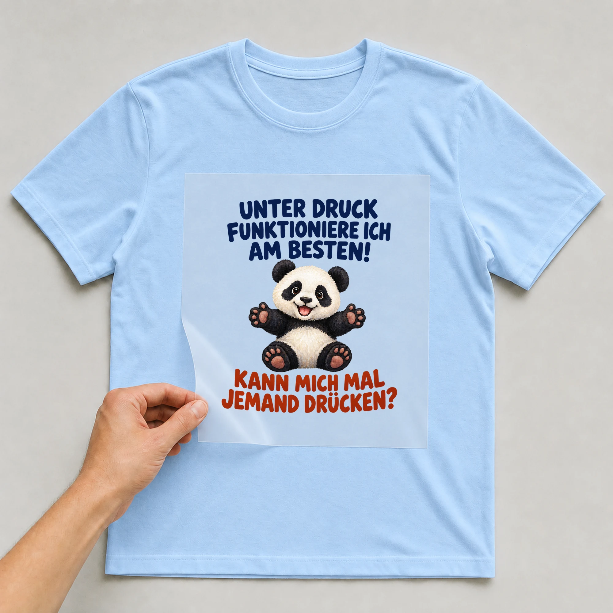 Bügelbild „Unter Druck funktioniere ich am besten! Kann mich mal jemand drücken?“ auf babyblauem T-Shirt, Folie wird aufgelegt