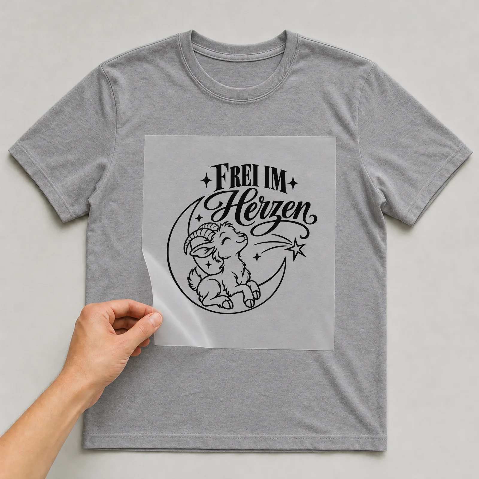 Bügelbild „Frei im Herzen“ auf grauem T-Shirt, Folie wird aufgelegt