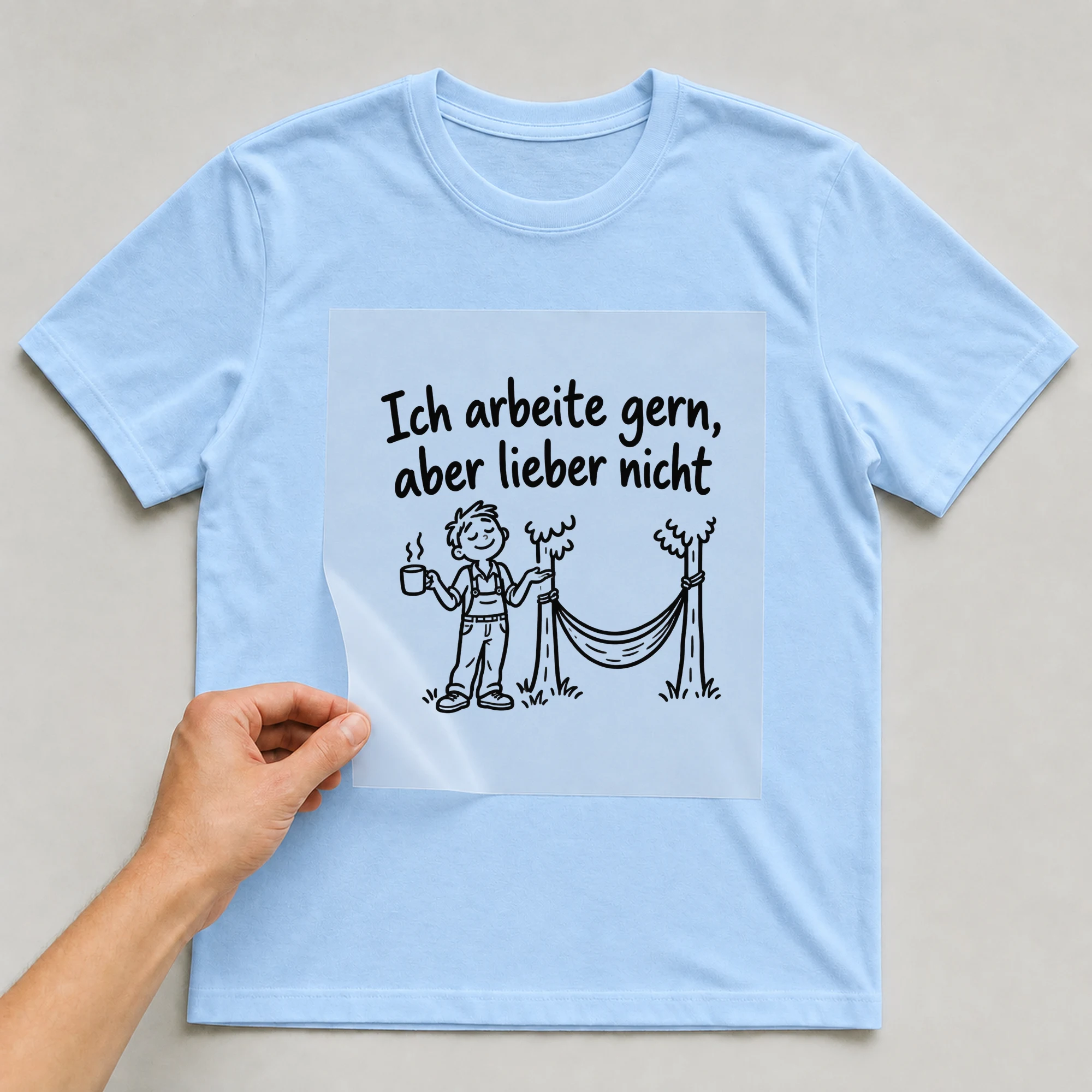 Bügelbild „Ich arbeite gern, aber lieber nicht“ auf babyblauem T-Shirt, Folie wird aufgelegt