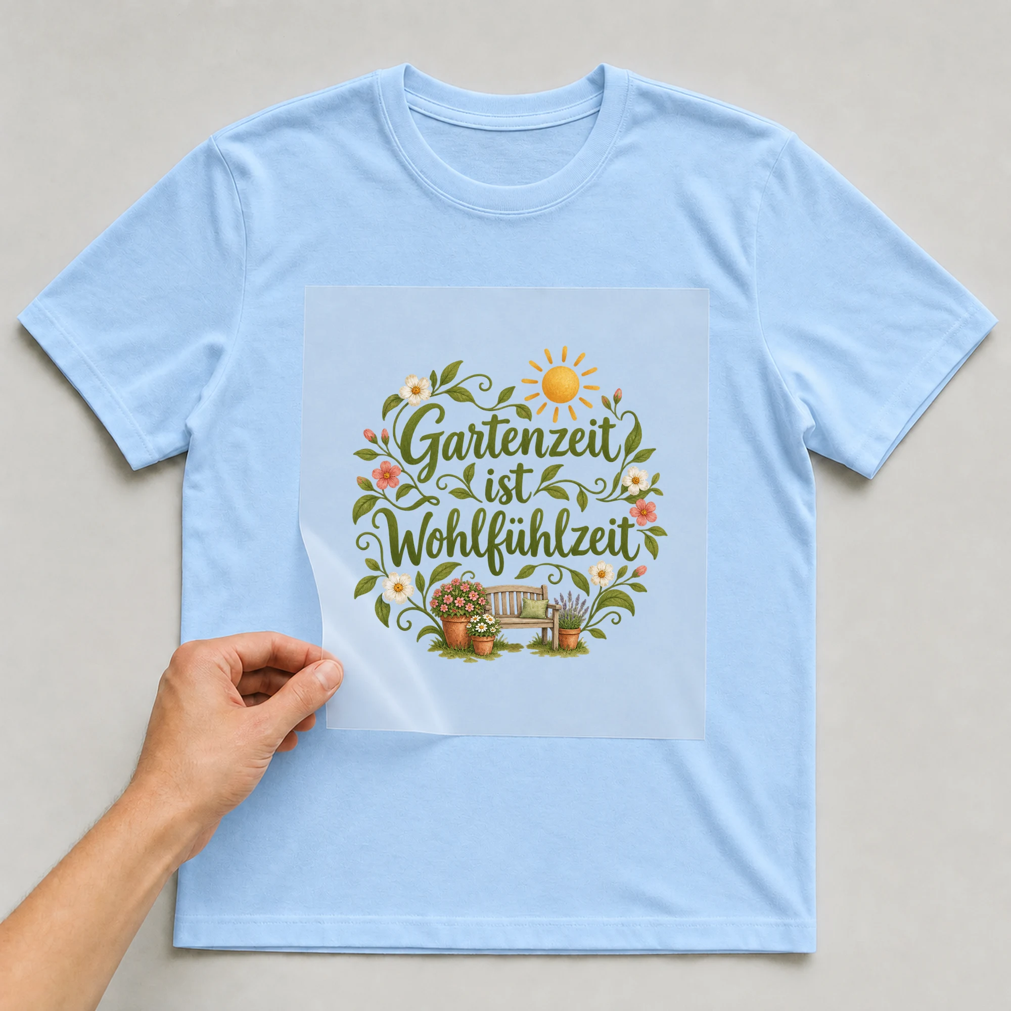 Bügelbild „Gartenzeit ist Wohlfühlzeit“ auf babyblauem T-Shirt, Folie wird aufgelegt
