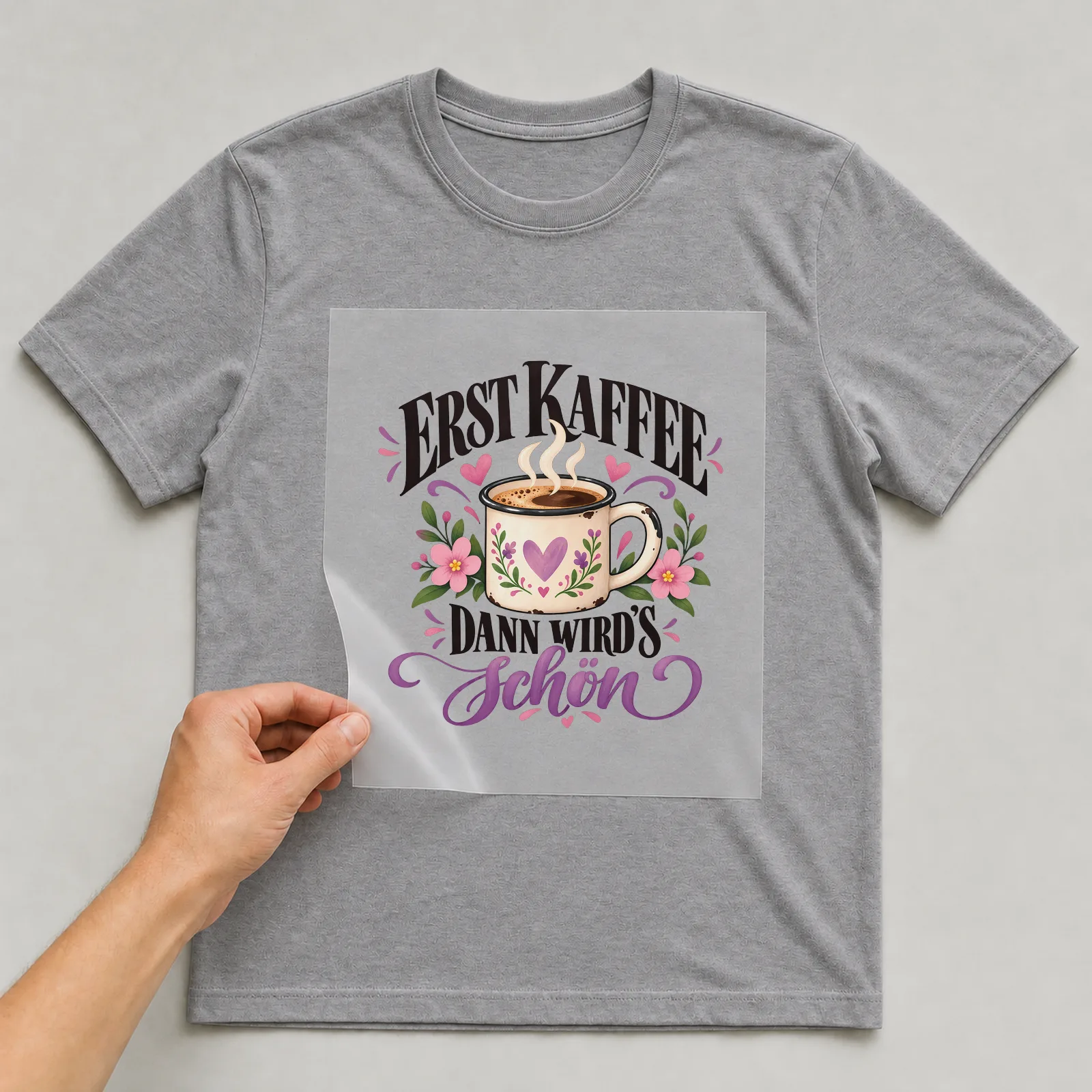Bügelbild „Erst Kaffee dann wird’s schön“ auf grauem T-Shirt, Folie wird aufgelegt
