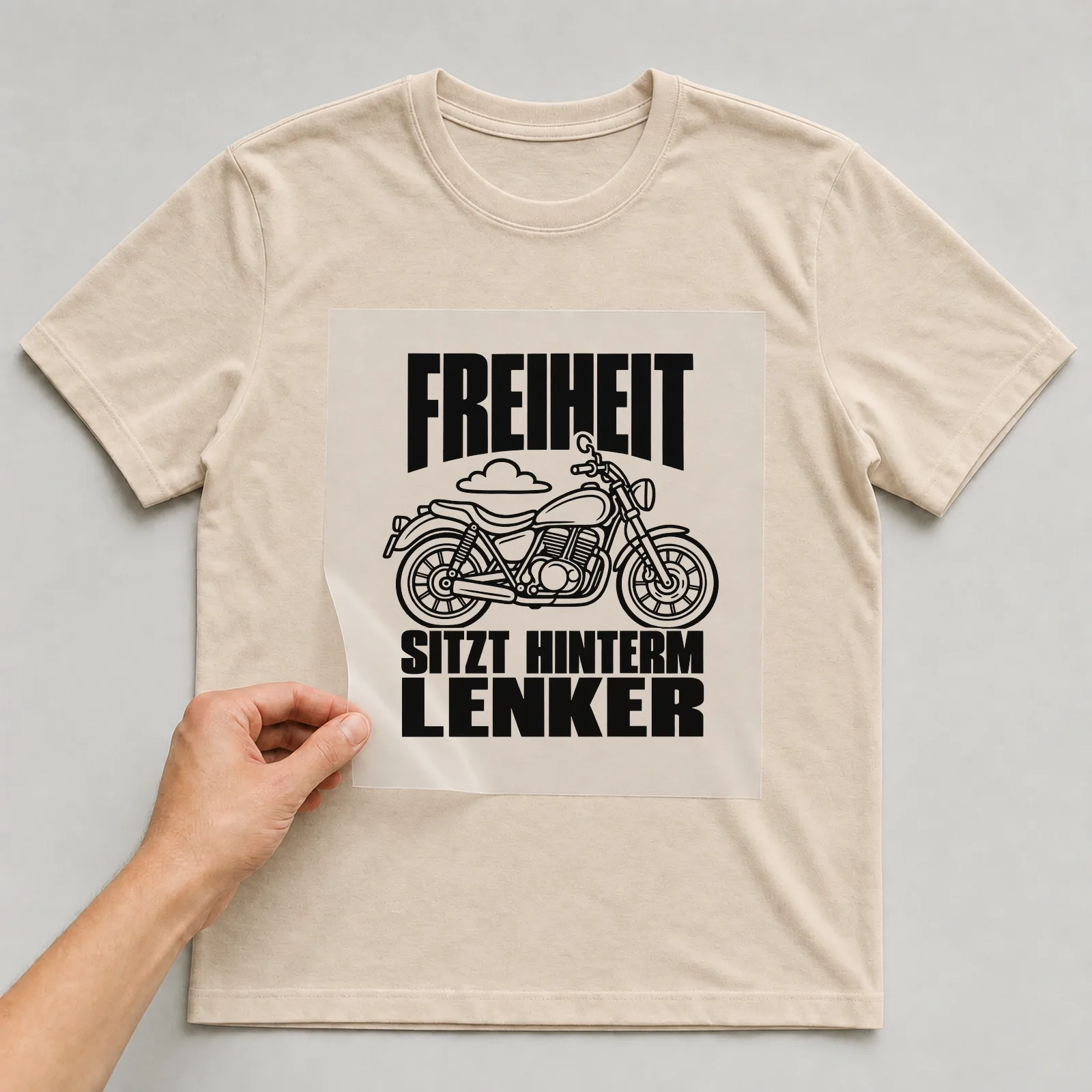 Bügelbild „Freiheit sitzt hinterm Lenker“ auf beigem T-Shirt, Folie wird aufgelegt