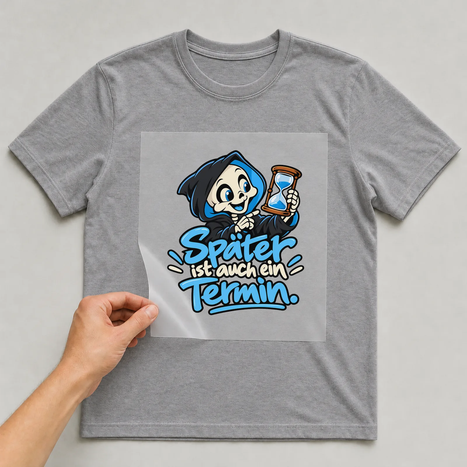 Bügelbild „Später ist auch ein Termin“ auf grauem T-Shirt, Folie wird aufgelegt