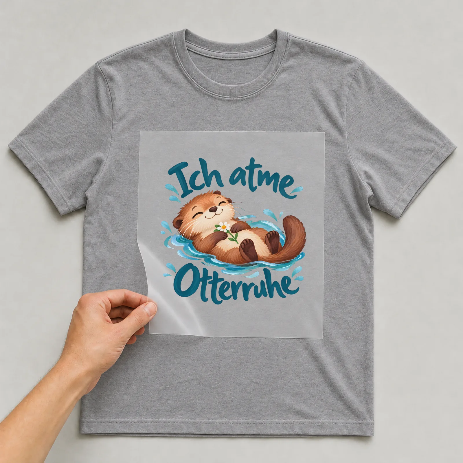 Bügelbild „Ich atme Otterruhe“ auf grauem T-Shirt, Folie wird aufgelegt