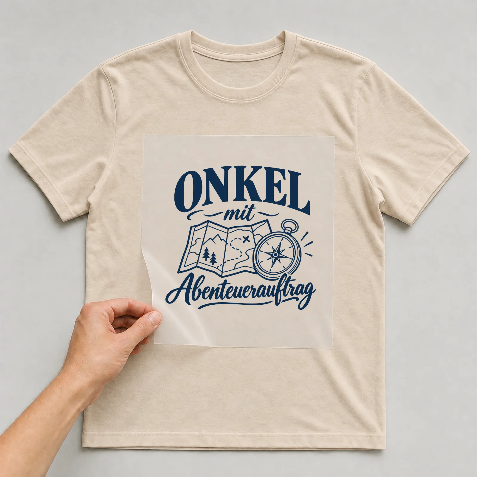 Bügelbild „Onkel mit Abenteuerauftrag“ auf beigem T-Shirt, Folie wird aufgelegt