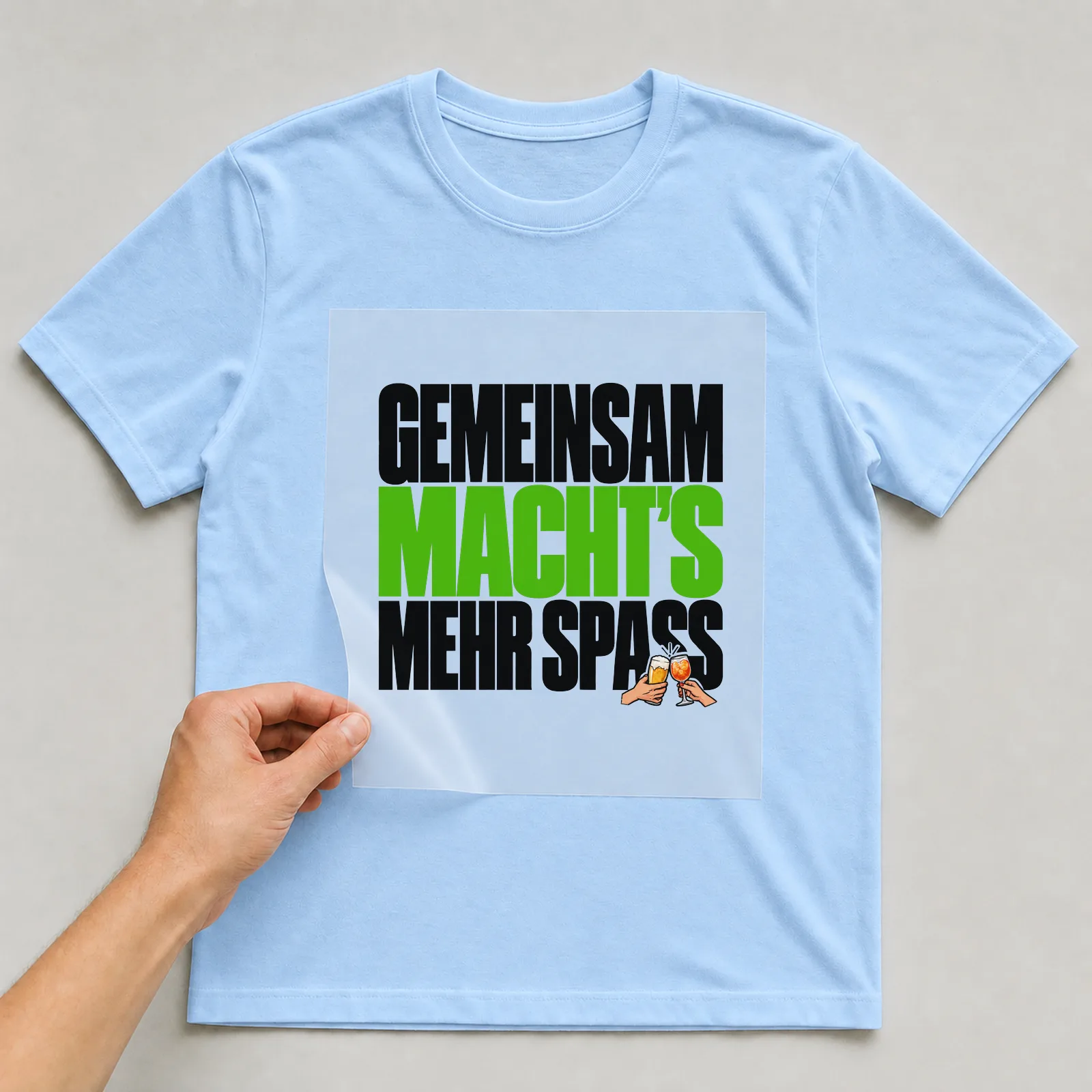 Bügelbild „Gemeinsam macht’s mehr Spass“ auf hellblauem T-Shirt, Folie wird aufgelegt