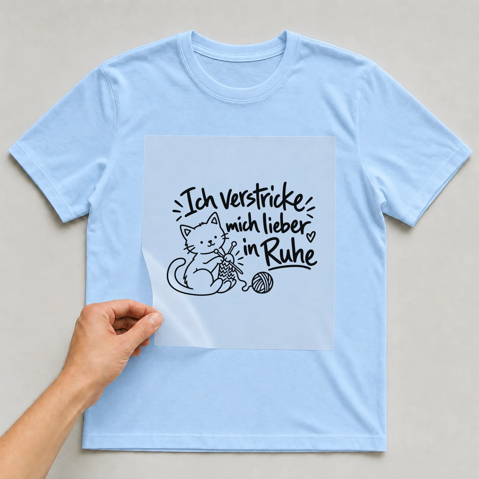 Bügelbild „Ich verstricke mich lieber in Ruhe“ auf hellblauem T-Shirt, Folie wird aufgelegt