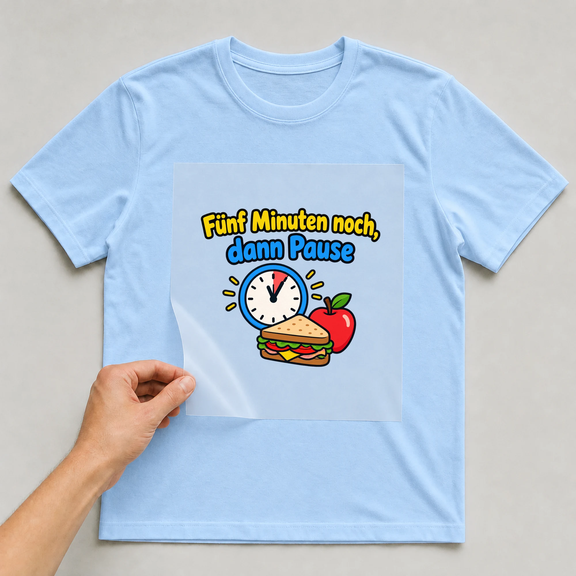Bügelbild „Fünf Minuten noch, dann Pause“ auf babyblauem T-Shirt, Folie wird aufgelegt
