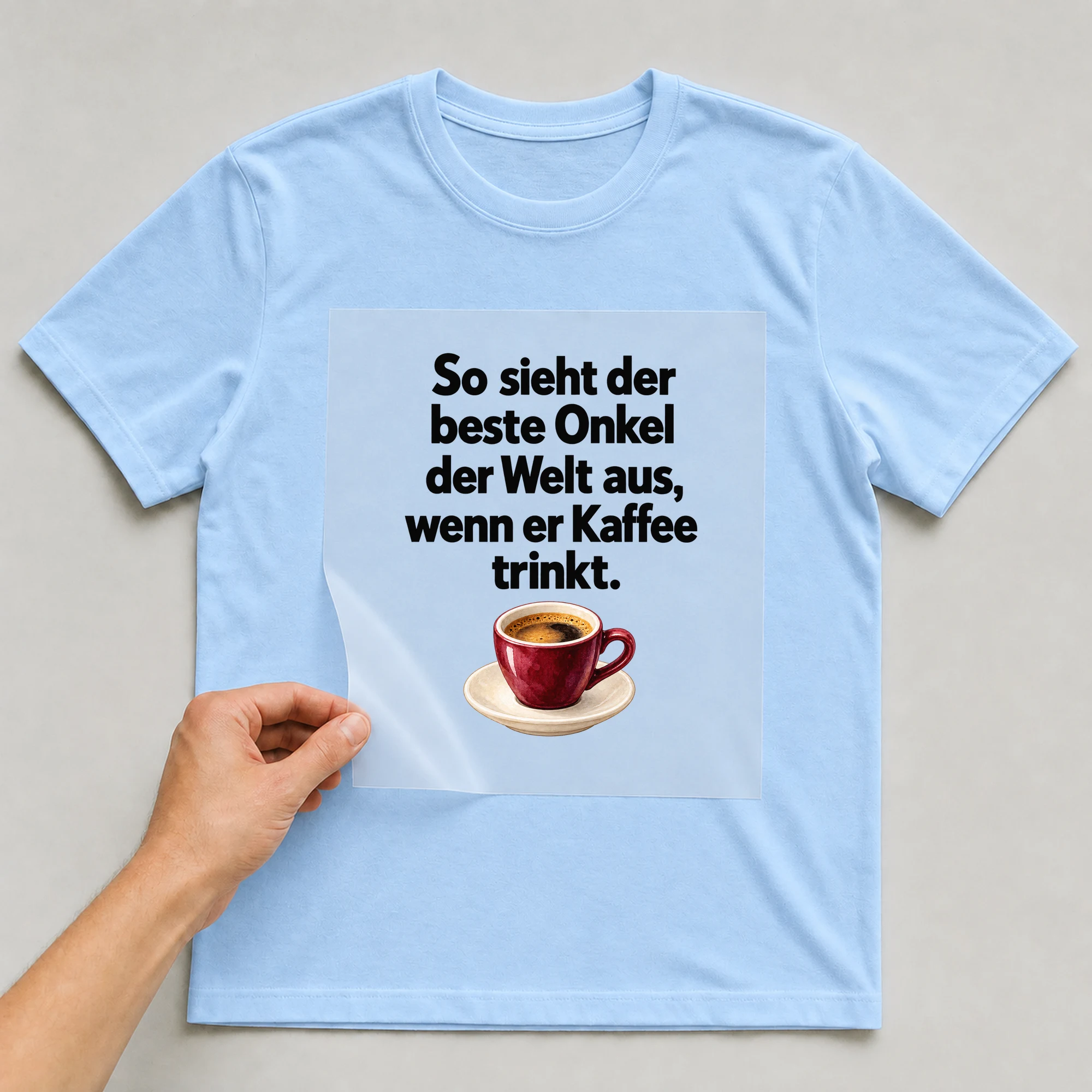 Bügelbild „So sieht der beste Onkel der Welt aus, wenn er Kaffee trinkt.“ auf babyblauem T-Shirt, Folie wird aufgelegt
