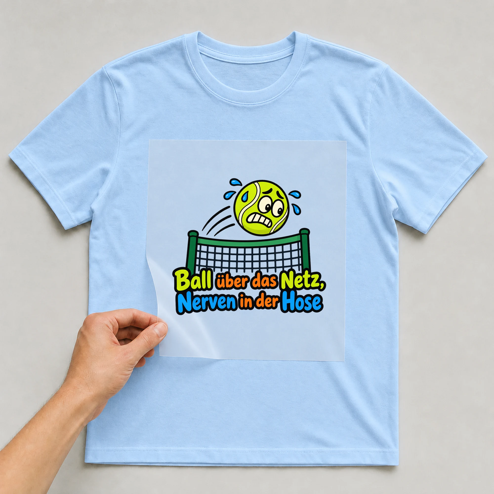 Bügelbild „Ball über das Netz, Nerven in der Hose“ auf babyblauem T-Shirt, Folie wird aufgelegt