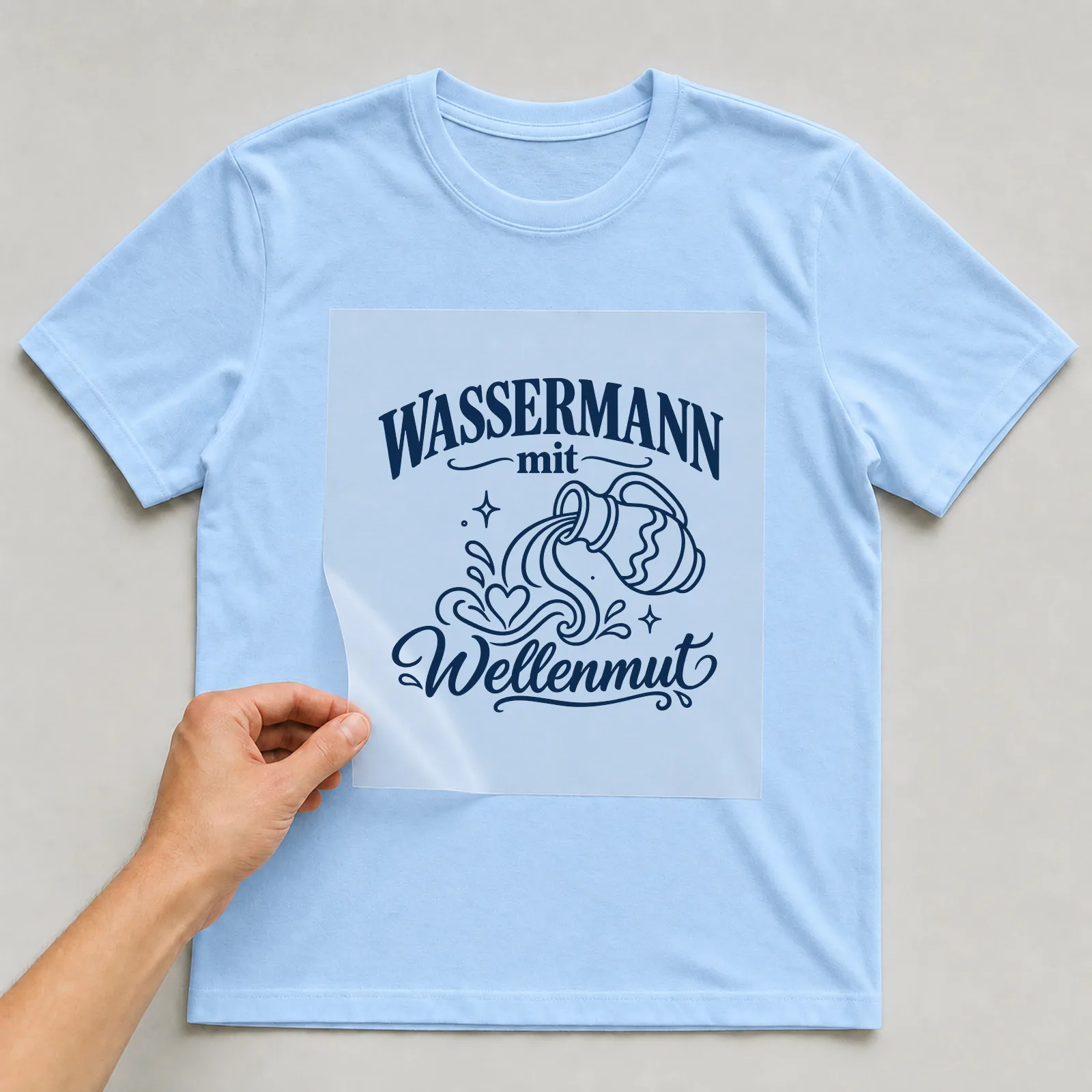 Bügelbild „Wassermann mit Wellenmut“ auf hellblauem T-Shirt, Folie wird aufgelegt