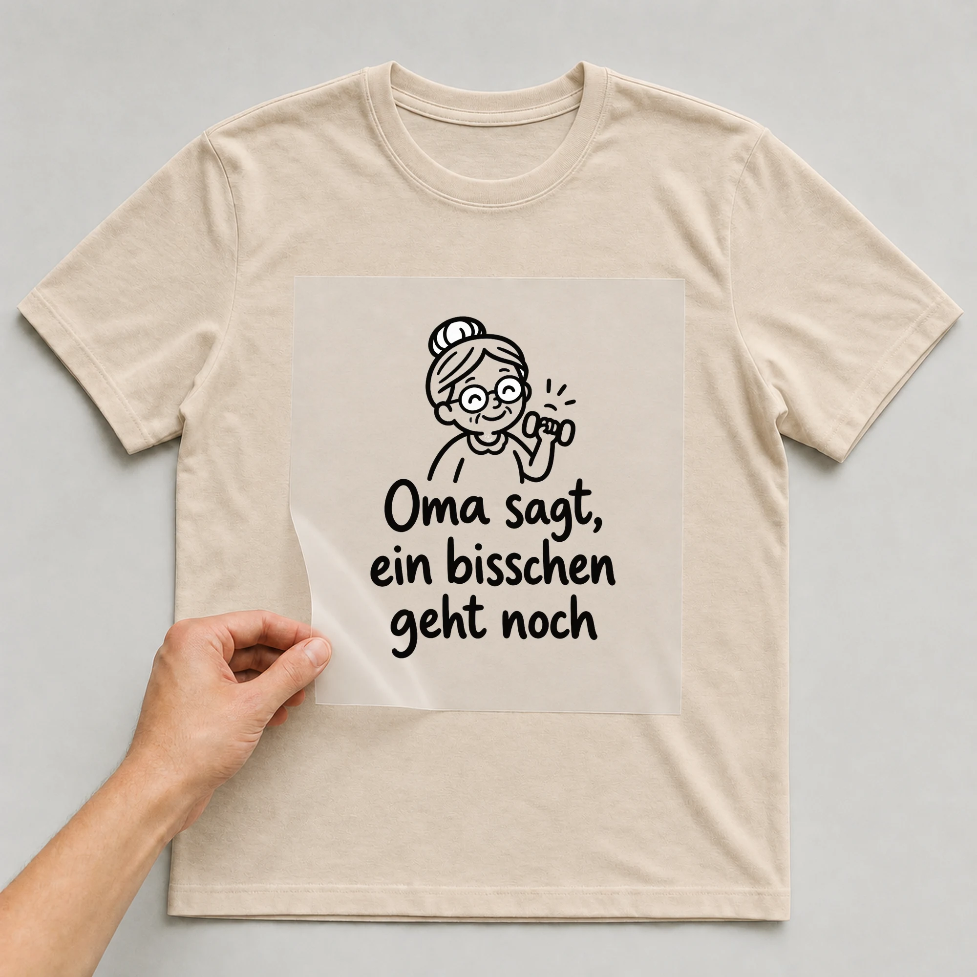 Bügelbild „Oma sagt, ein bisschen geht noch“ auf beigem T-Shirt, Folie wird aufgelegt