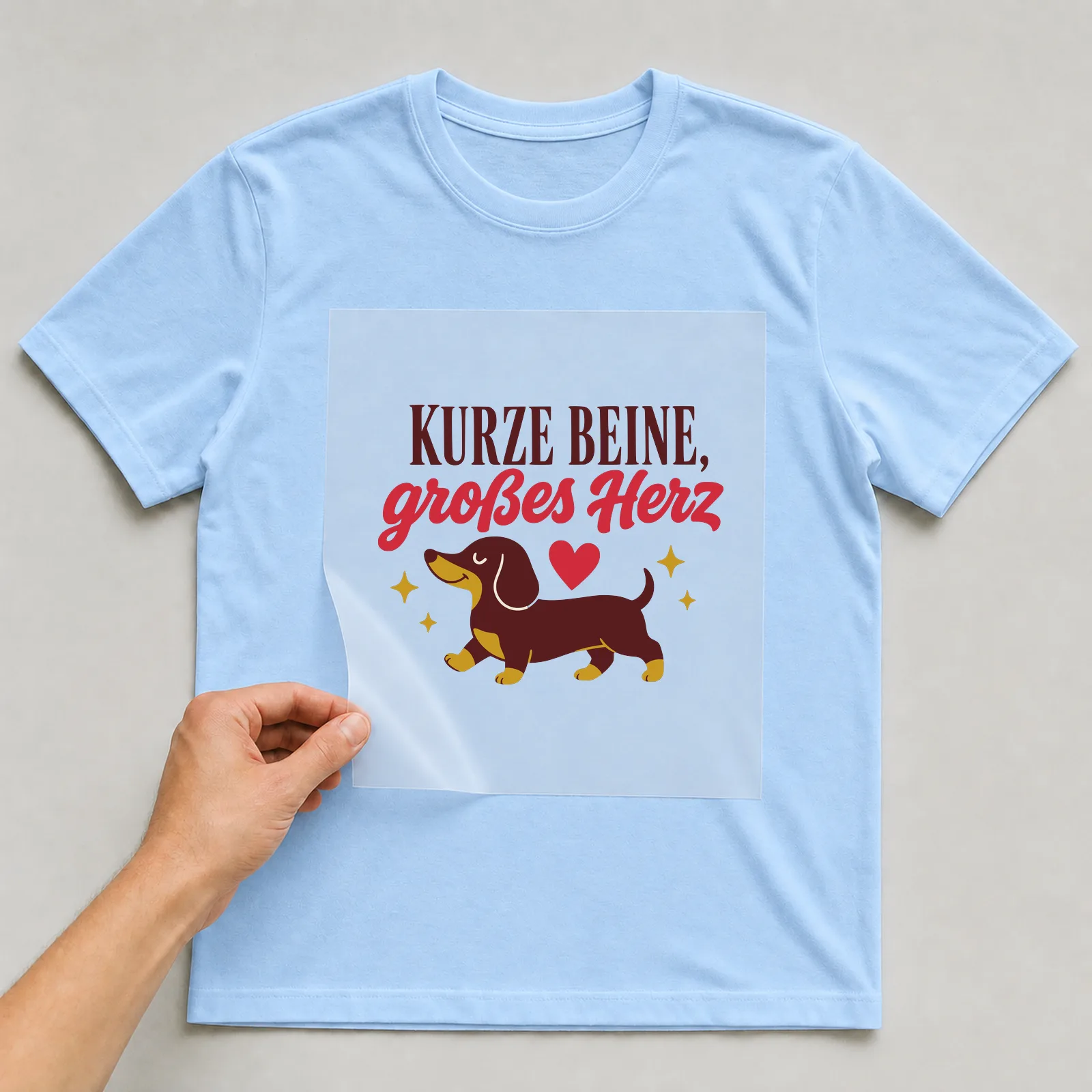 Bügelbild Kurze Beine, großes Herz auf hellblauem T-Shirt, Folie wird aufgelegt