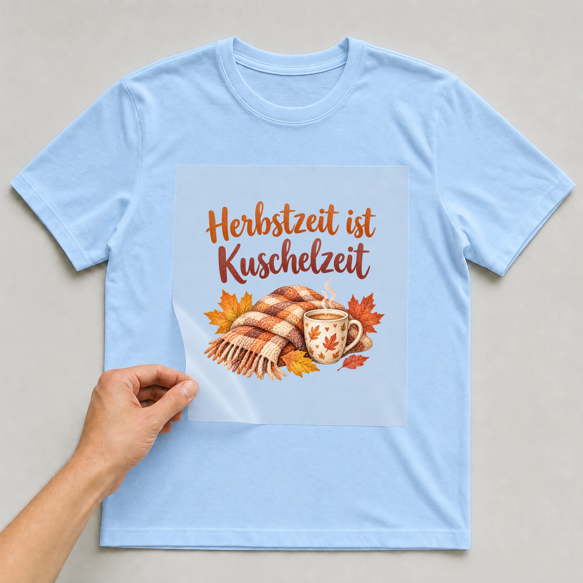 Bügelbild „Herbstzeit ist Kuschelzeit“ auf babyblauem T-Shirt, Folie wird aufgelegt